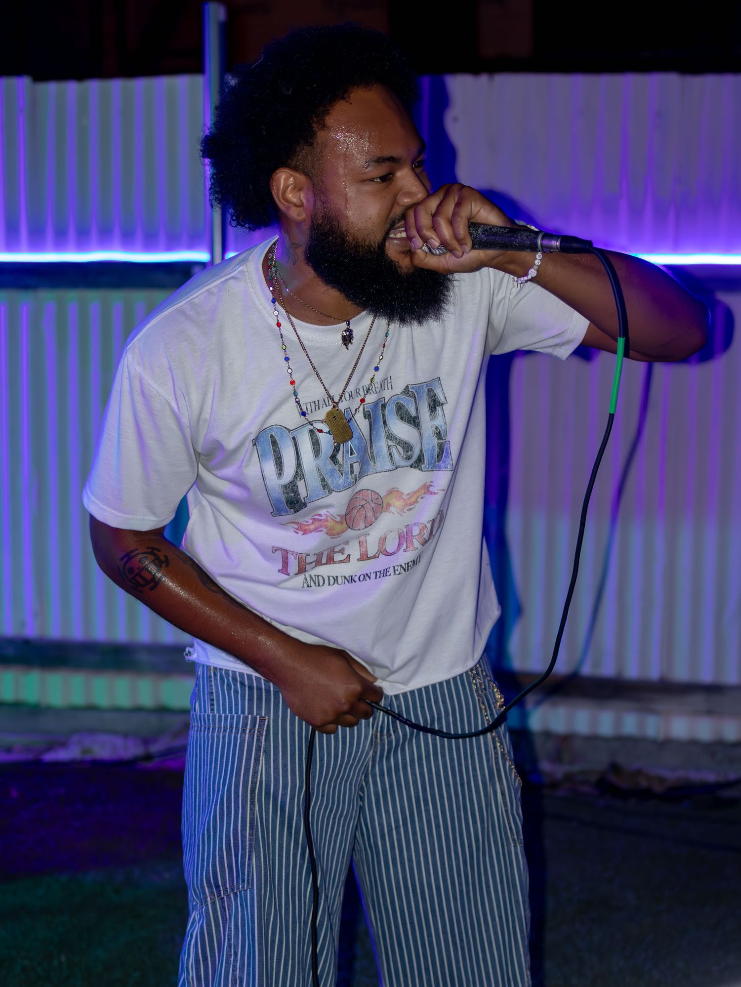 Hip hop artist performing passionately on stage under dramatic purple and blue lighting.