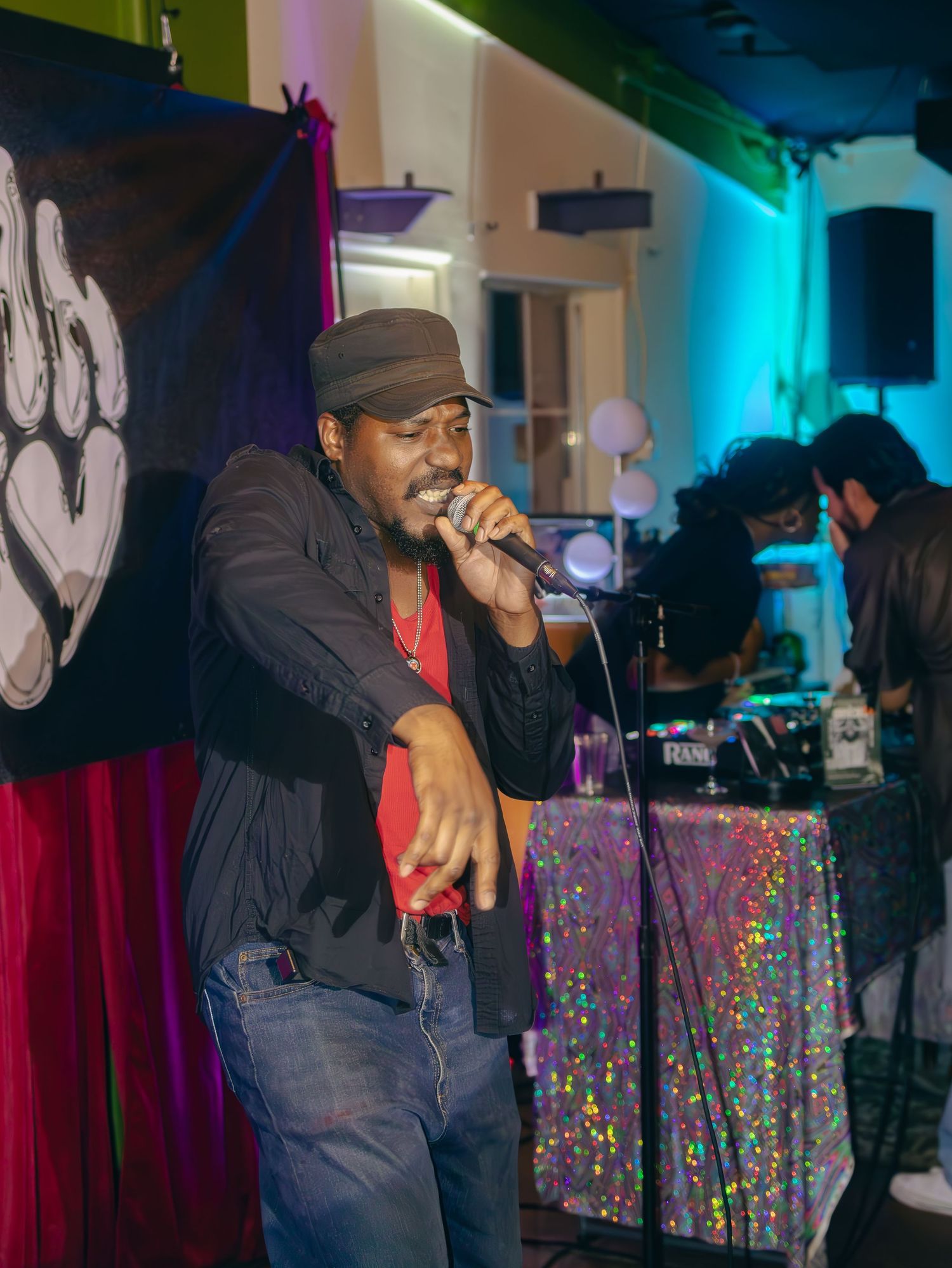 Entertainment venue with colorful accent lighting and sparkly table coverings during a performance.