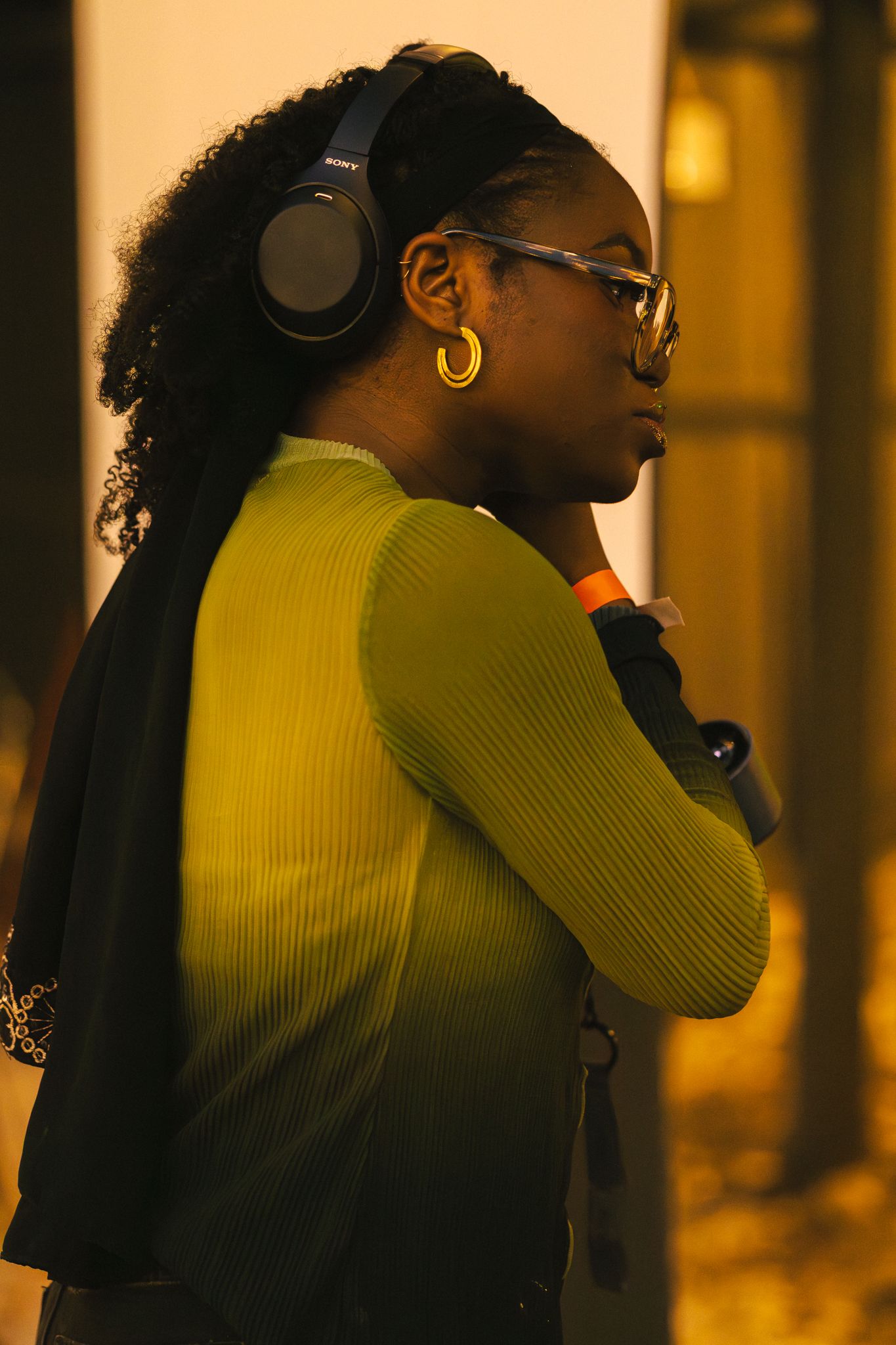 DJ silhouetted against warm yellow lighting while performing with headphones.