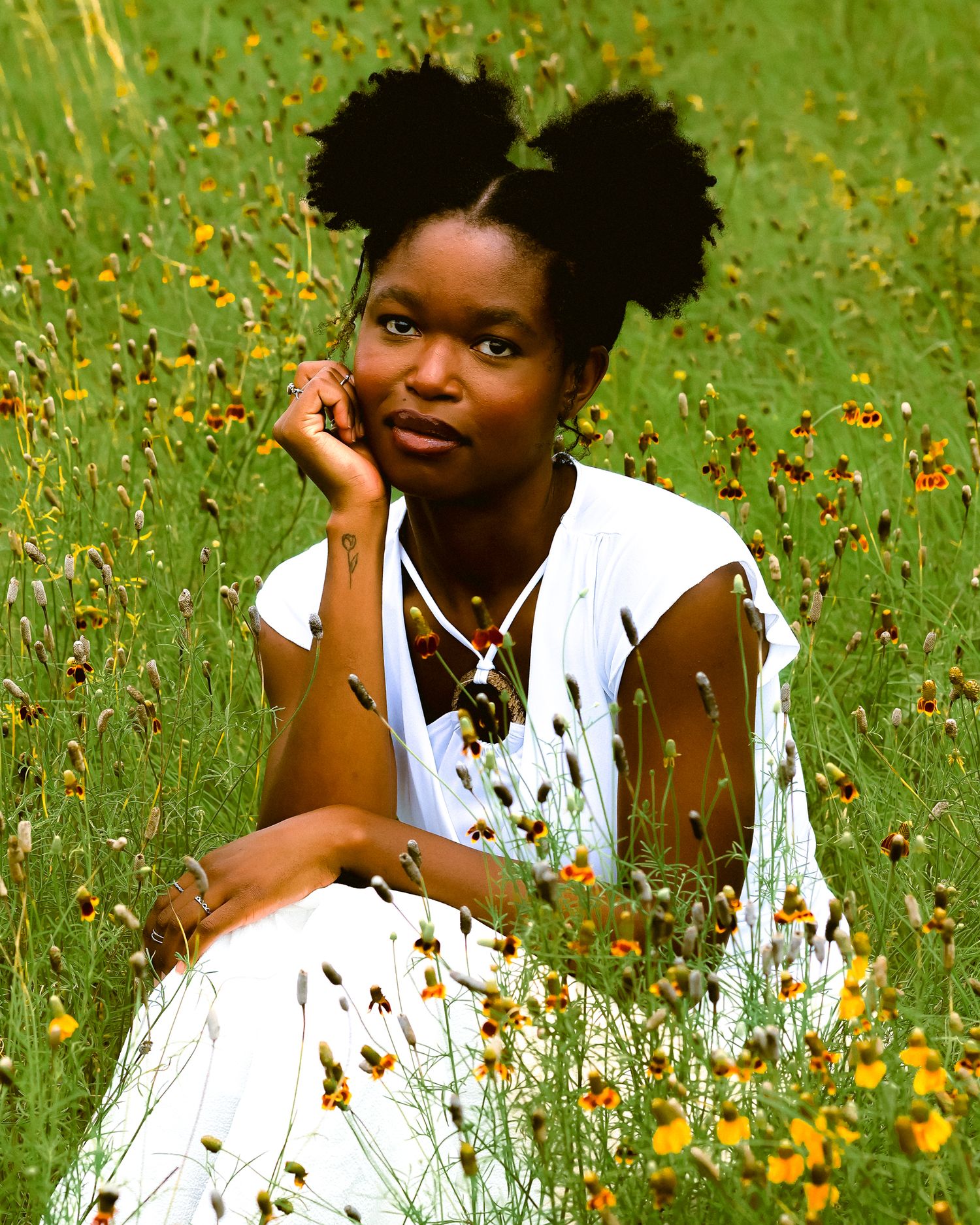 Portrait in white dress amid wildflowers with natural outdoor lighting.