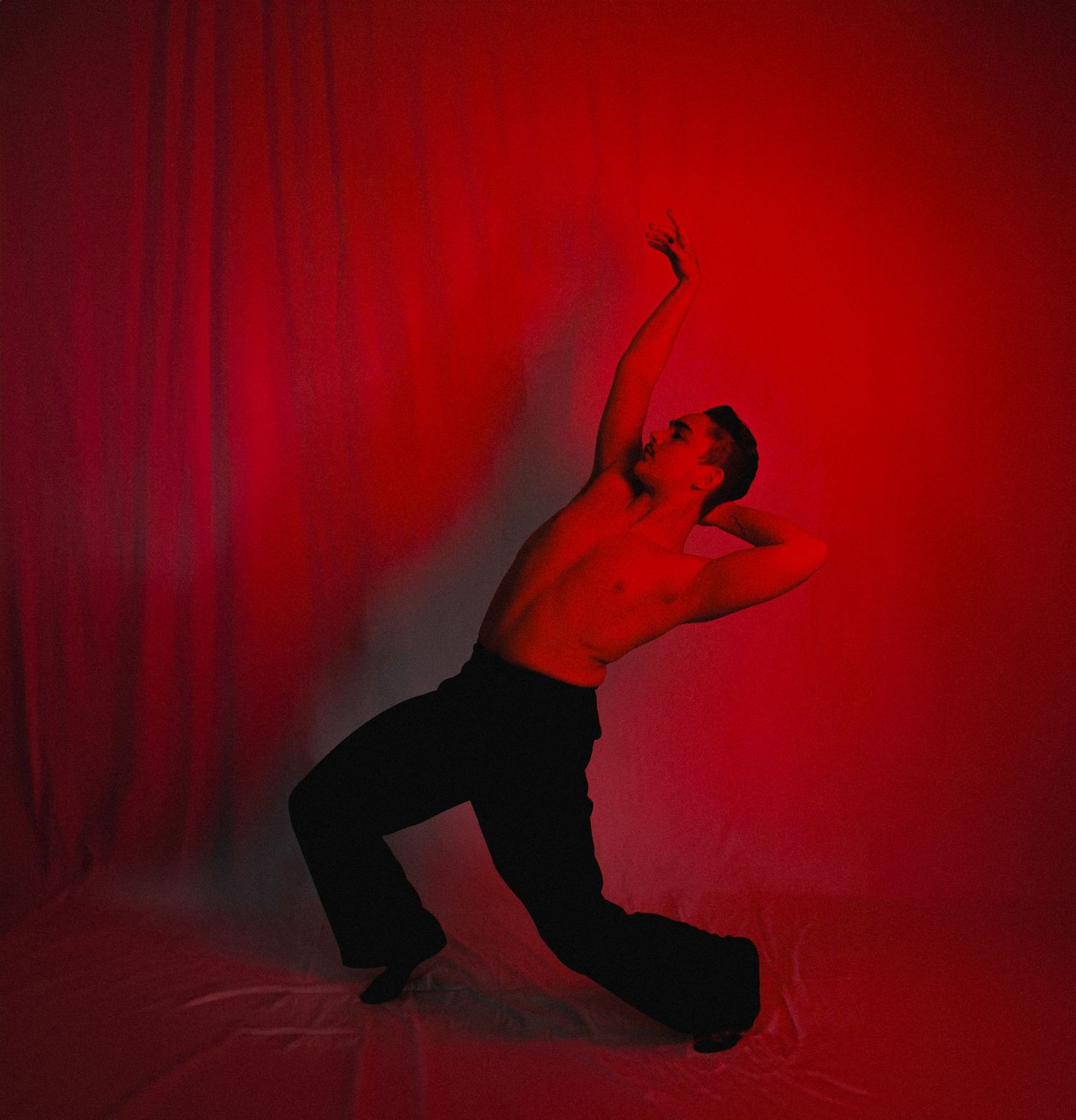 Silhouetted dancer performs against dramatic red lighting in artistic sequence.