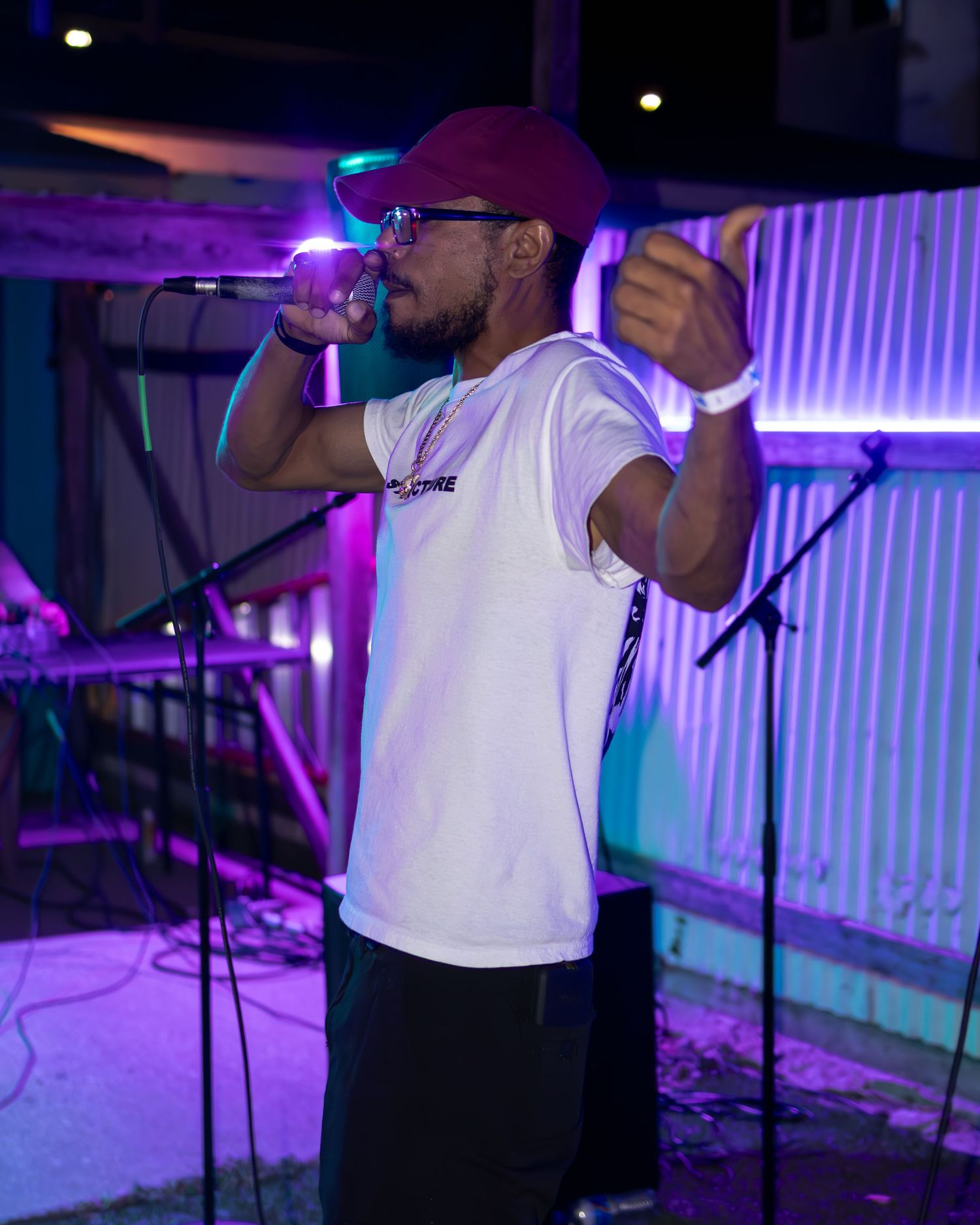 Stage performers in white shirts singing under purple and blue lighting effects.