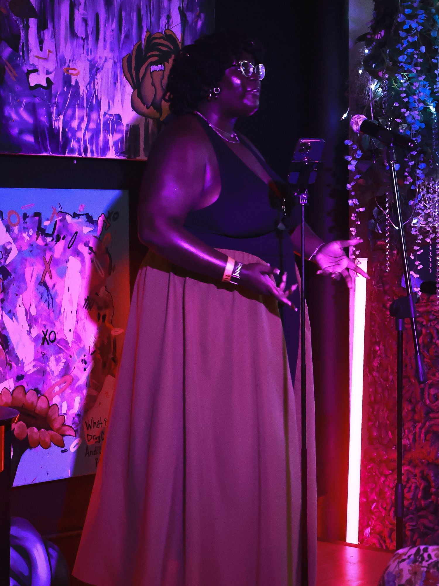 Performance space with dramatic lighting featuring purple hues and hanging decorative elements.