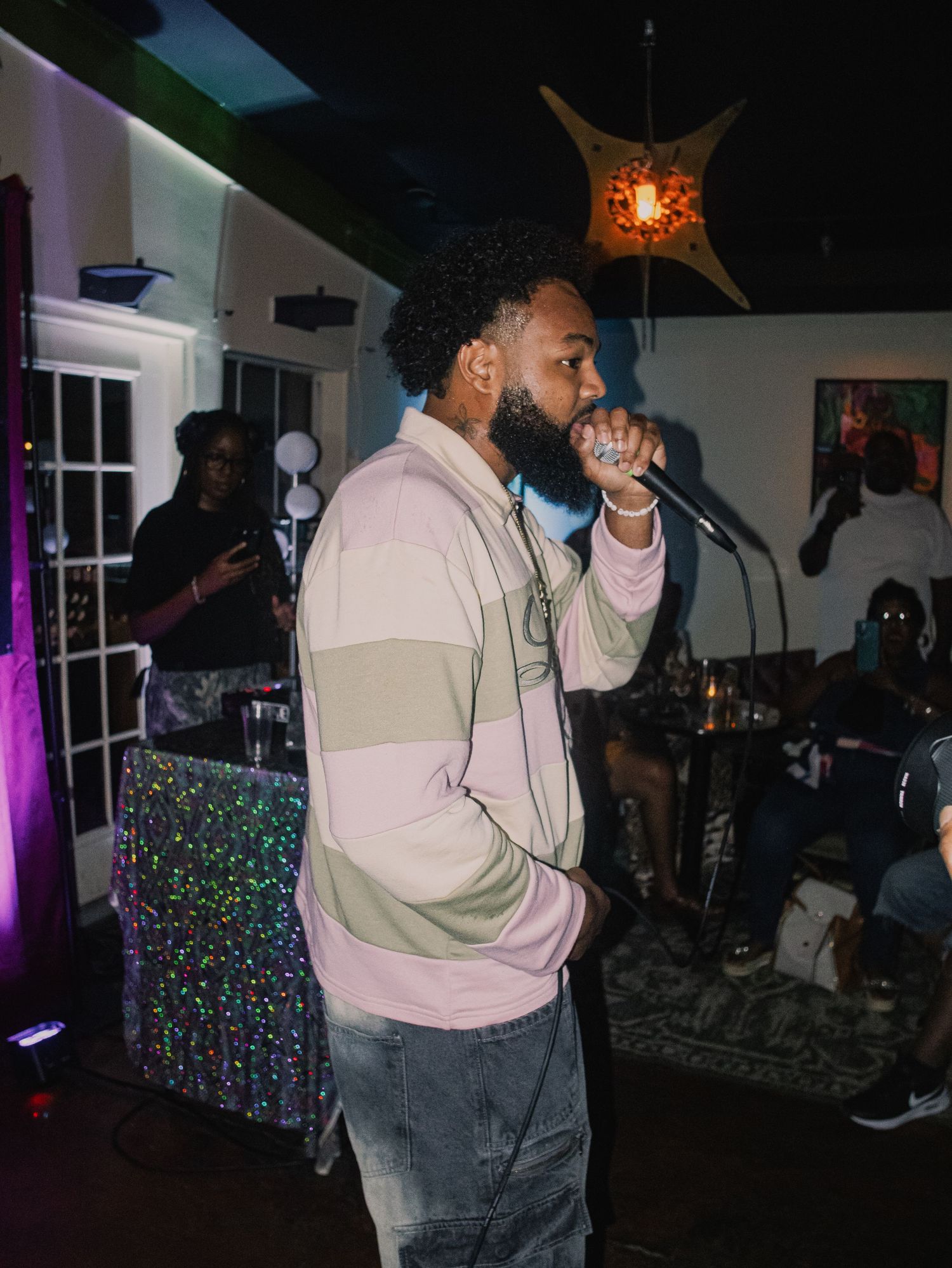 Performer in two-tone jacket entertaining crowd in intimate venue setting.