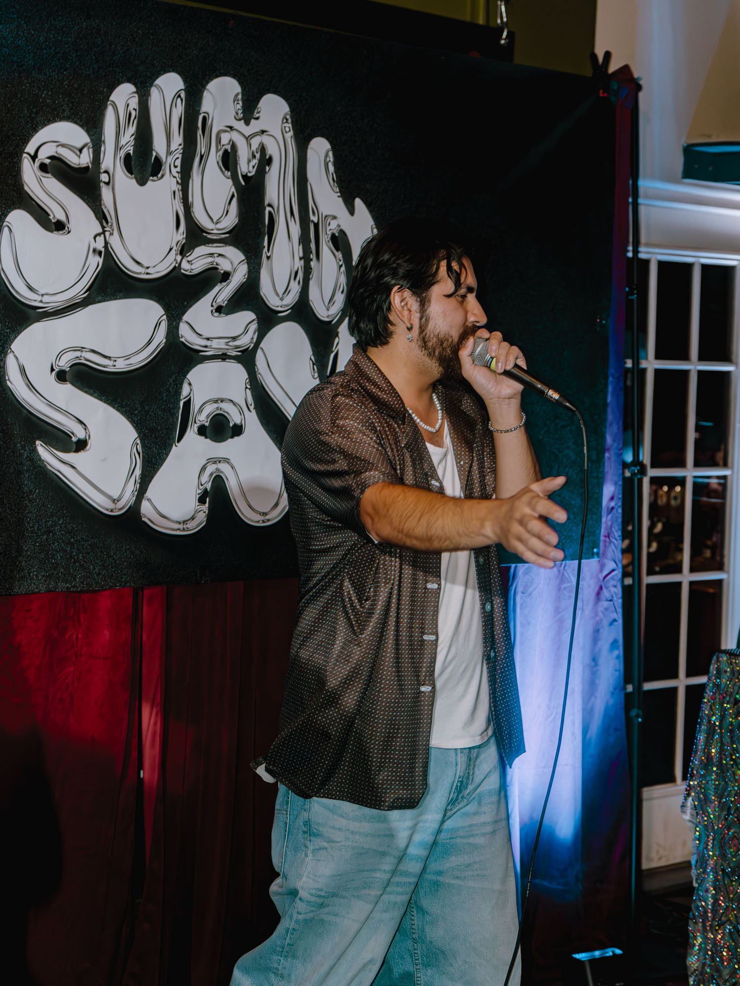 Performer singing on stage with graffiti-style backdrop and blue lighting effects.