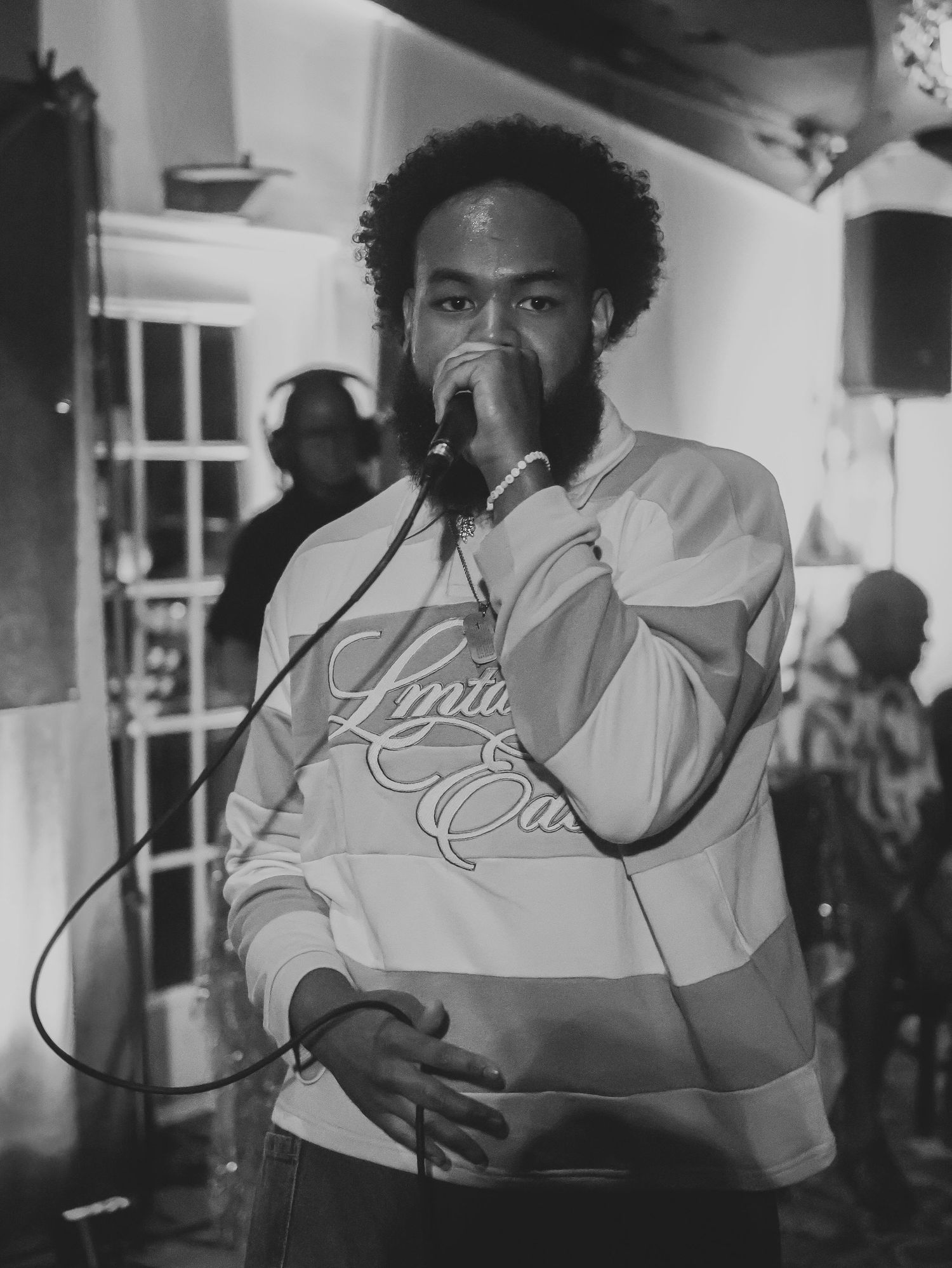 A black and white performance shot showing intense emotion and stage presence.