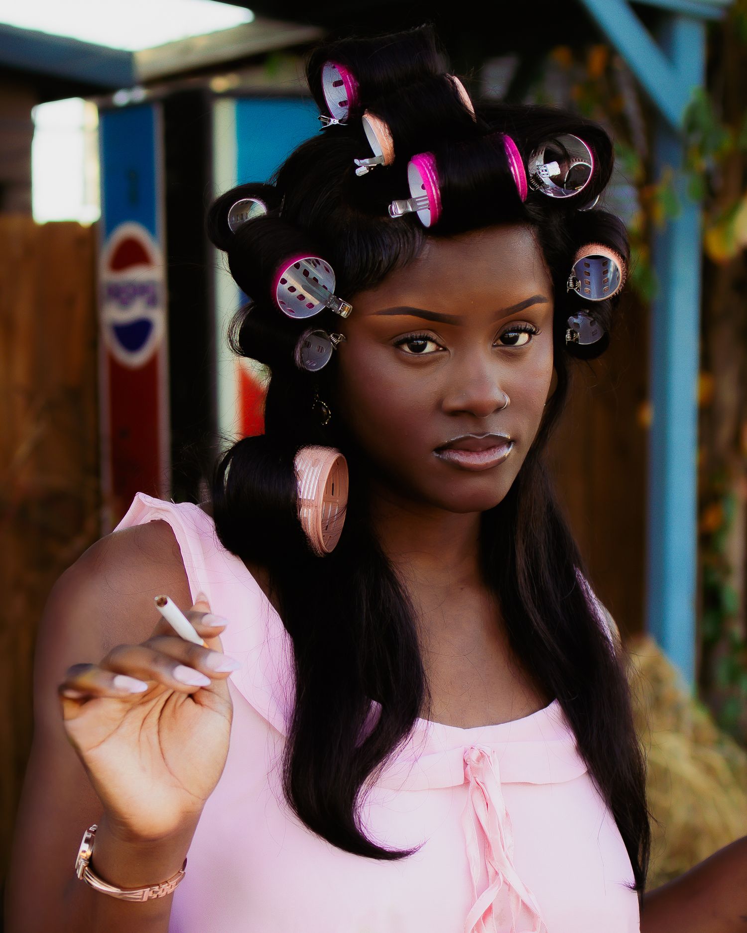 Stylish portrait series showing pink dress and hair rollers in urban setting.