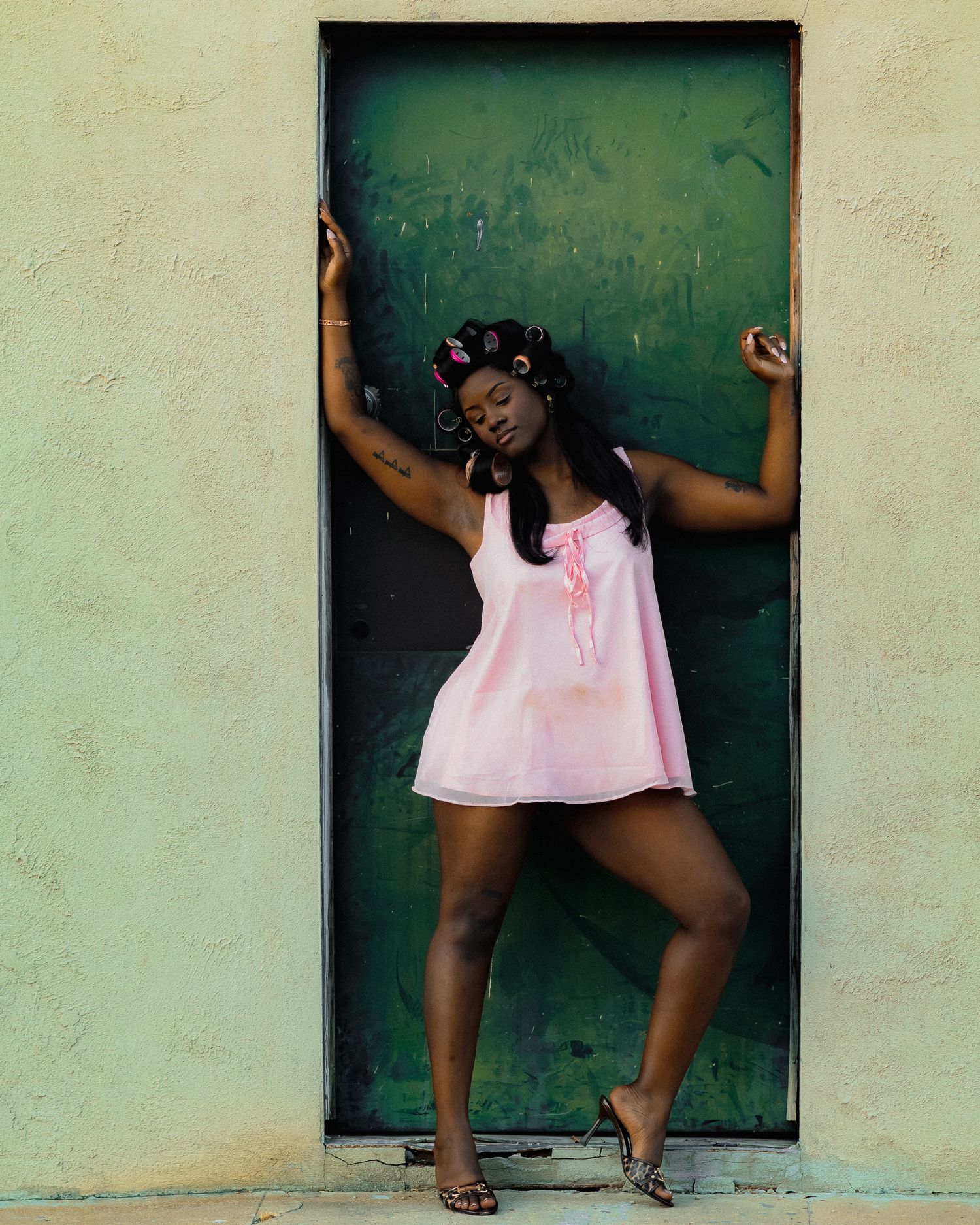 Expressive poses in pink attire against a minimalist backdrop with green door.