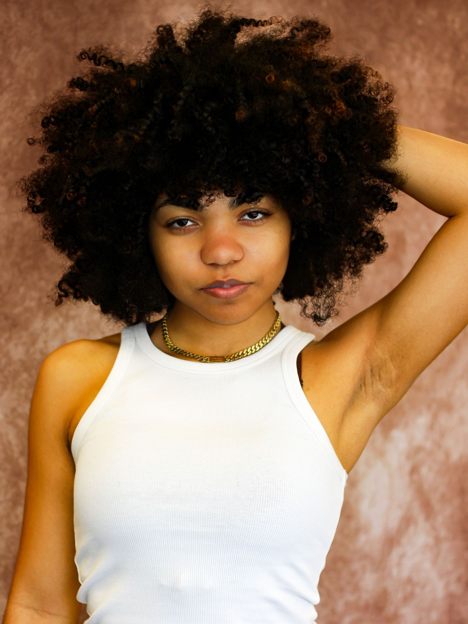 Portrait series in white tank top against textured brown backdrop.