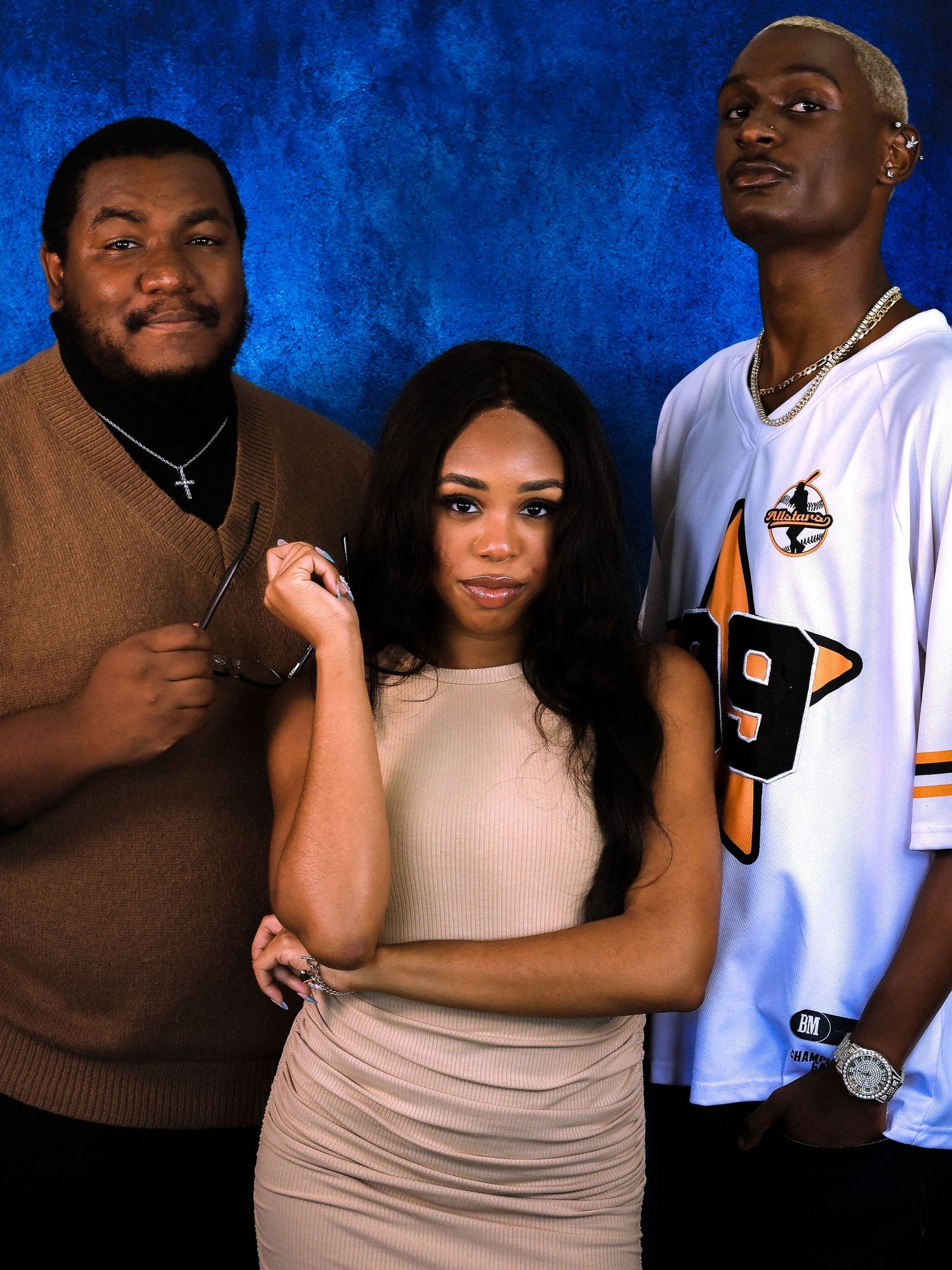 Casual group portrait session with varying poses against blue backdrop.