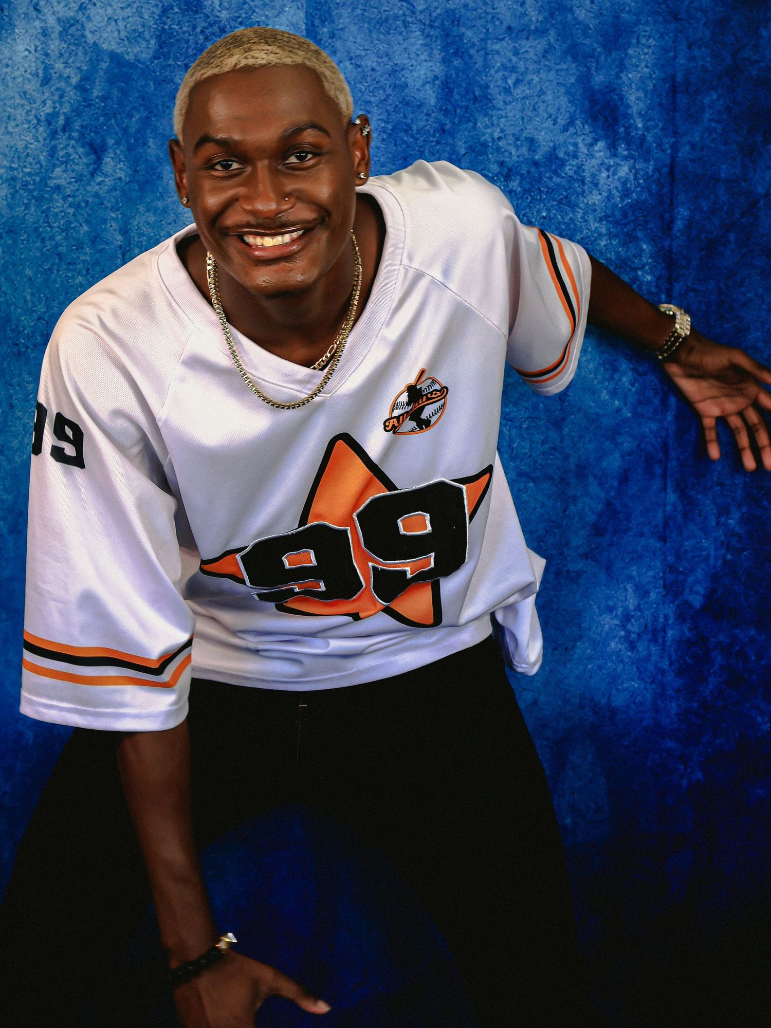 A person in a white jersey with number 99 poses against a blue background.