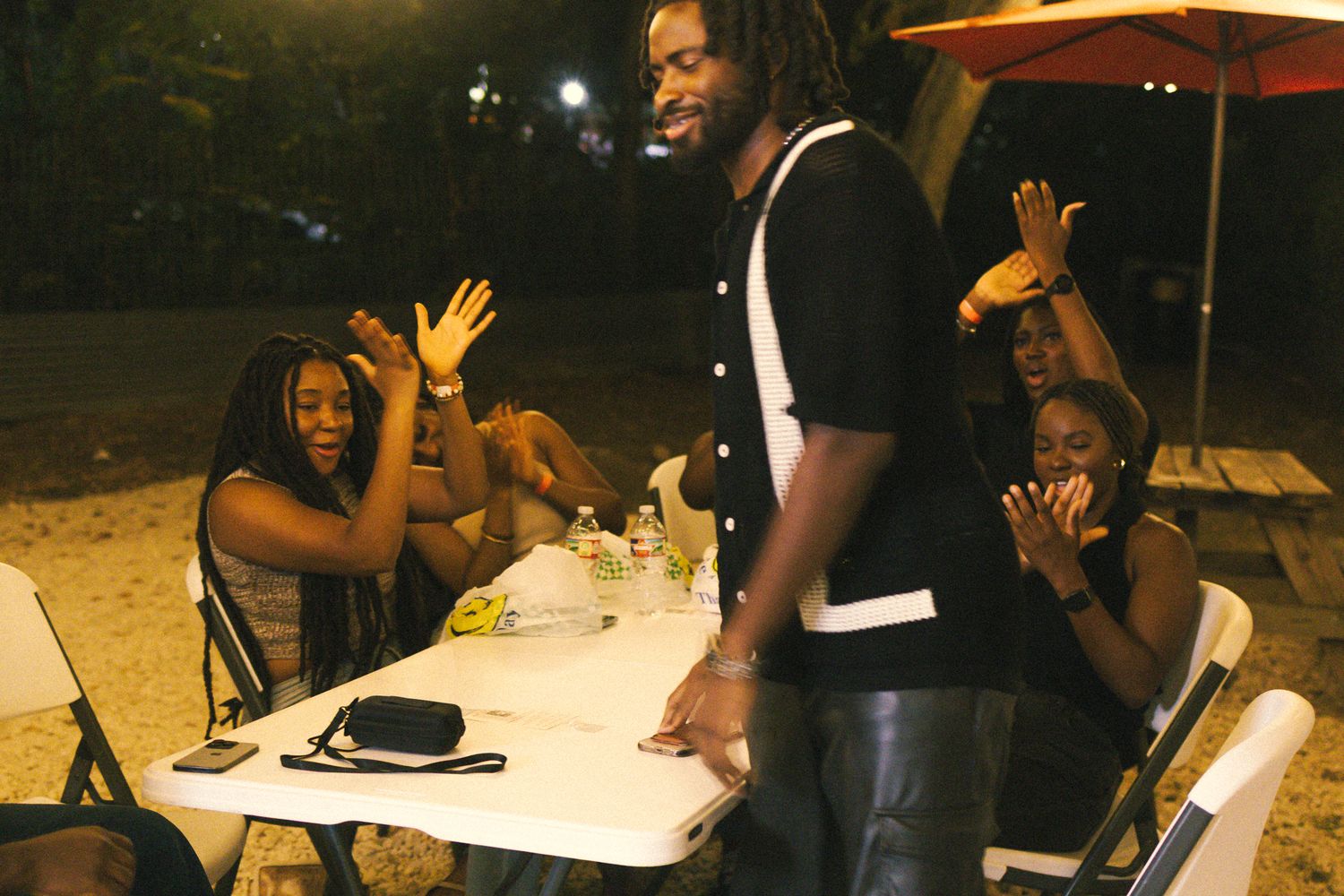 People reacting enthusiastically during an outdoor social event under string lights.
