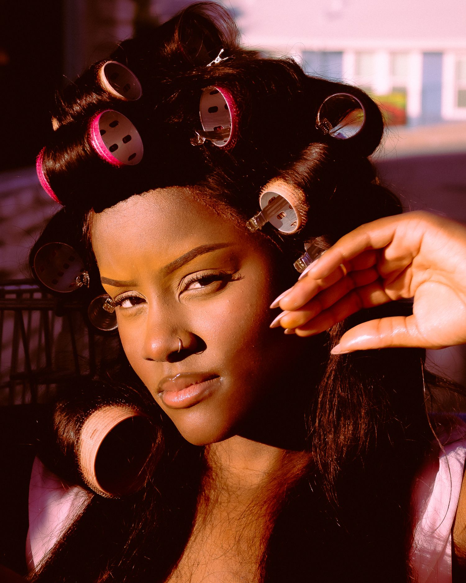 Close-up beauty shots with hair rollers and expressive poses in warm lighting.