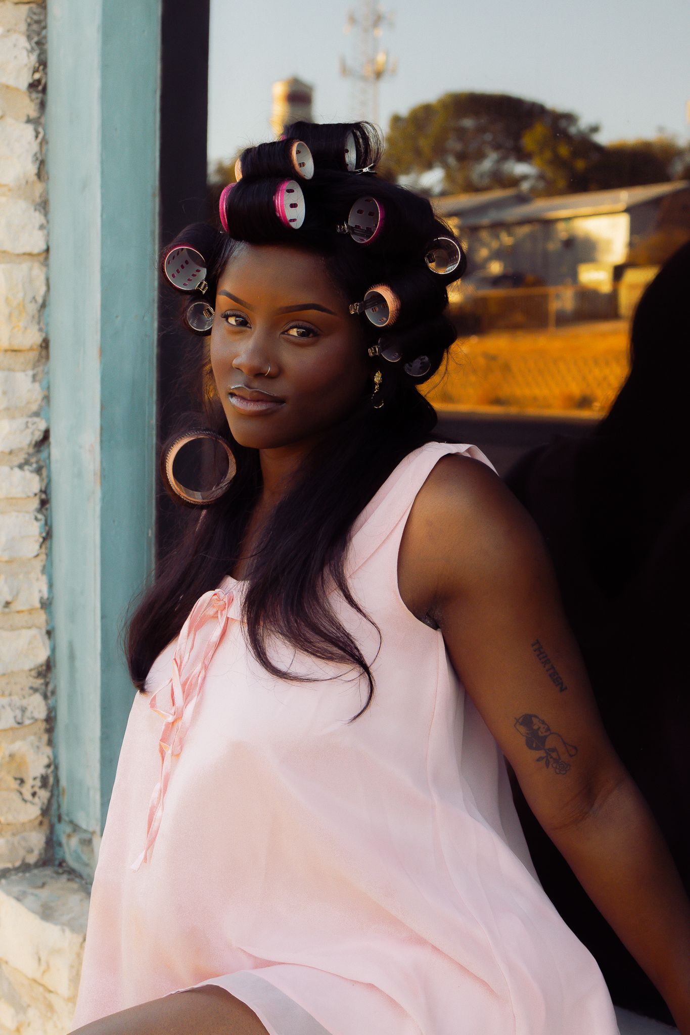 Portrait against stone wall showing pink top and styled hair.
