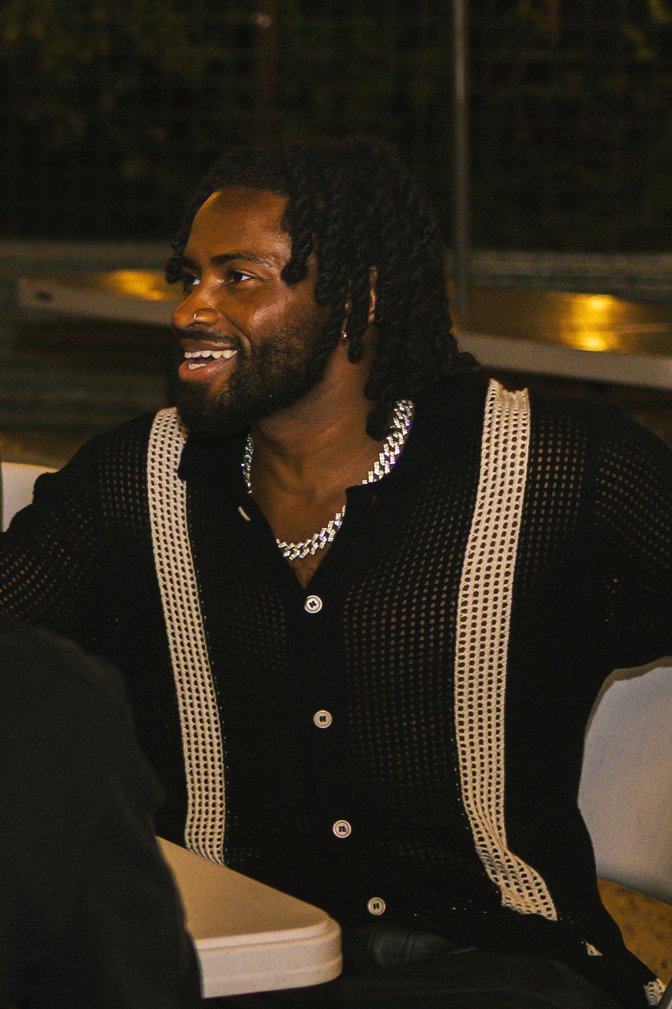 Person wearing black mesh shirt with white stripes at outdoor evening event.