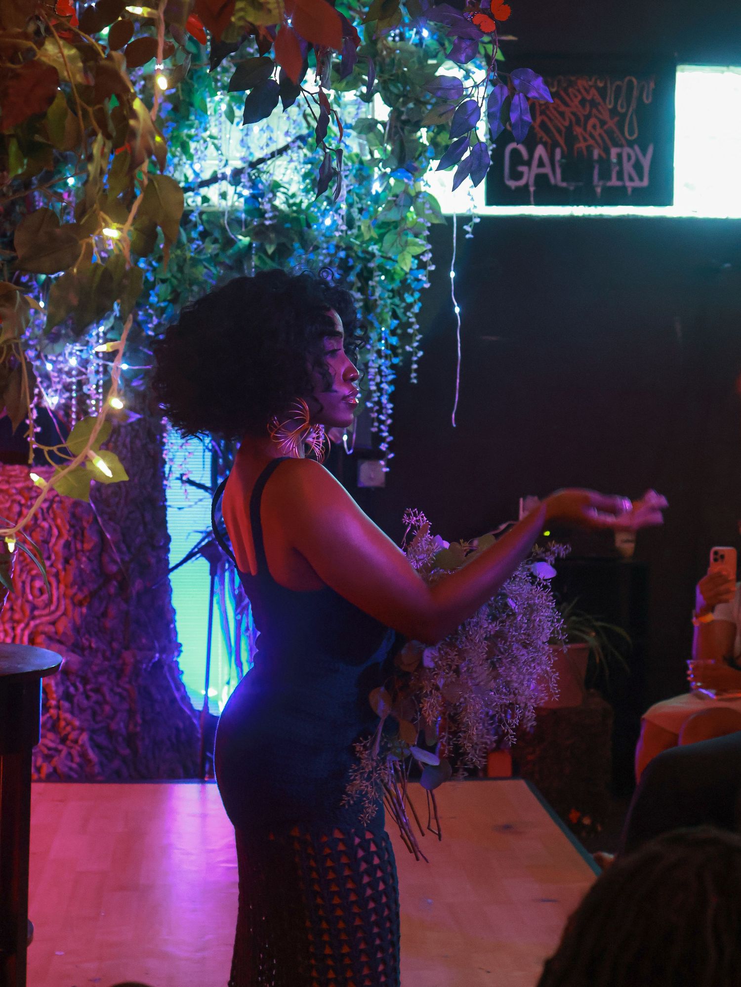 A dark venue space lit with neon pink and blue lights featuring decorative hanging elements.