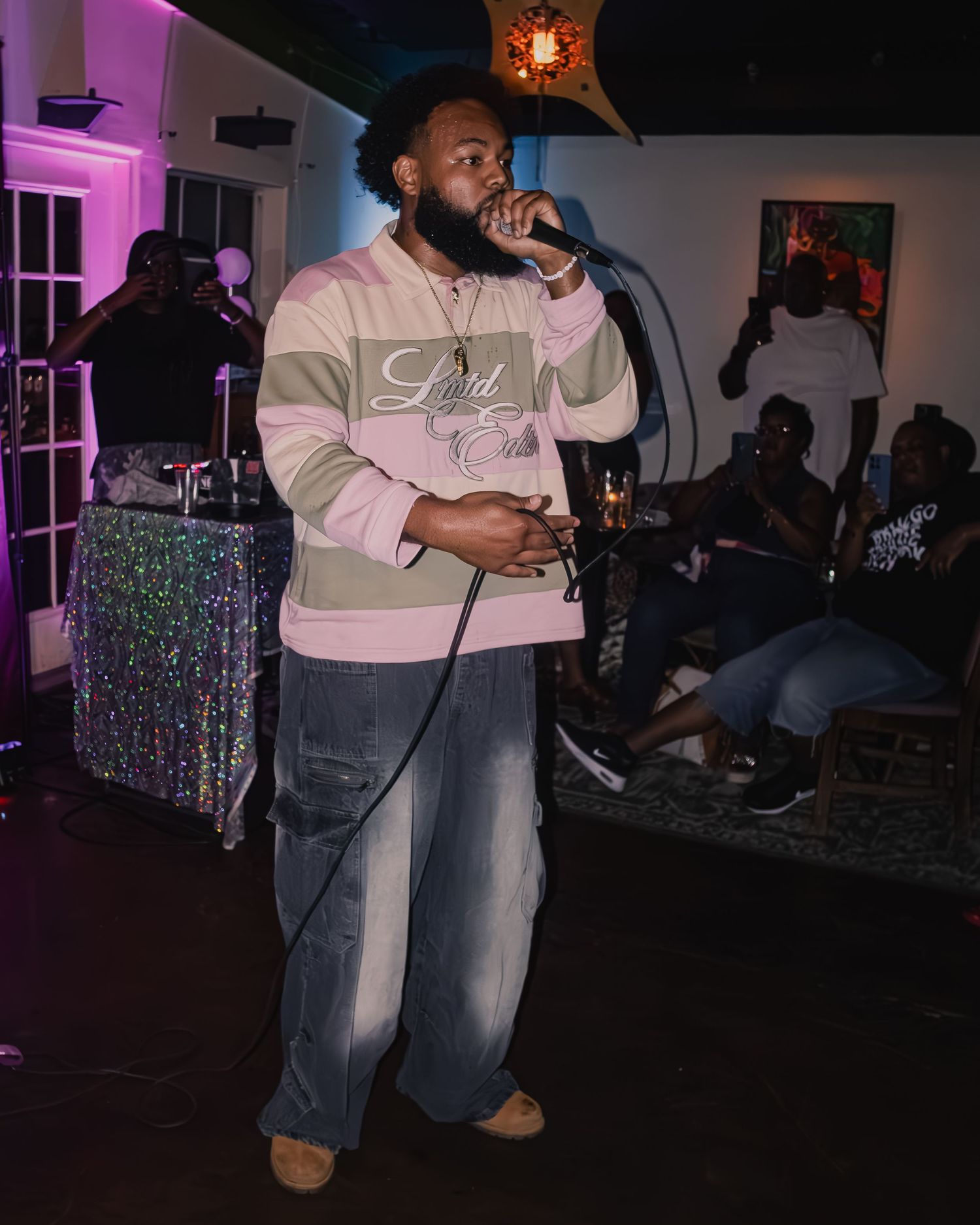 Performer in casual wear delivering passionate performance on dimly lit stage.