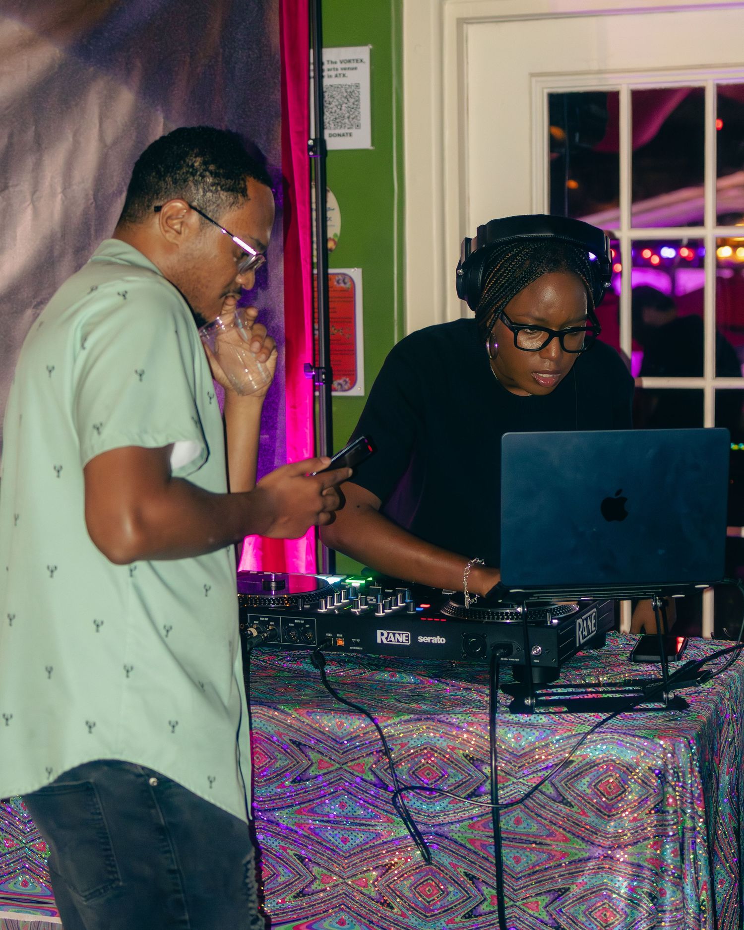 Two DJs collaborating at mixing table during nightclub performance.