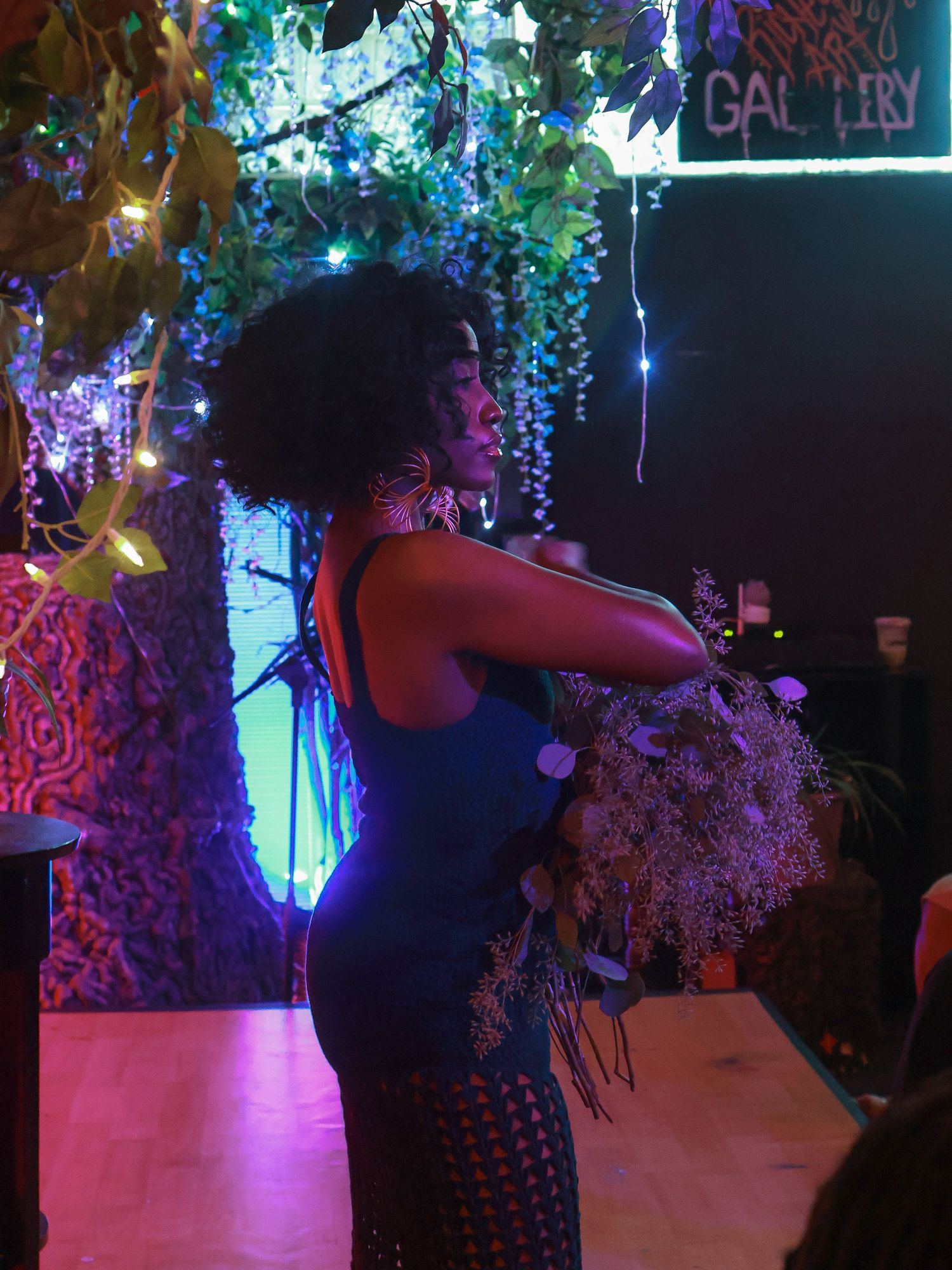 A nightclub interior decorated with hanging lights and floral elements against a dark background.