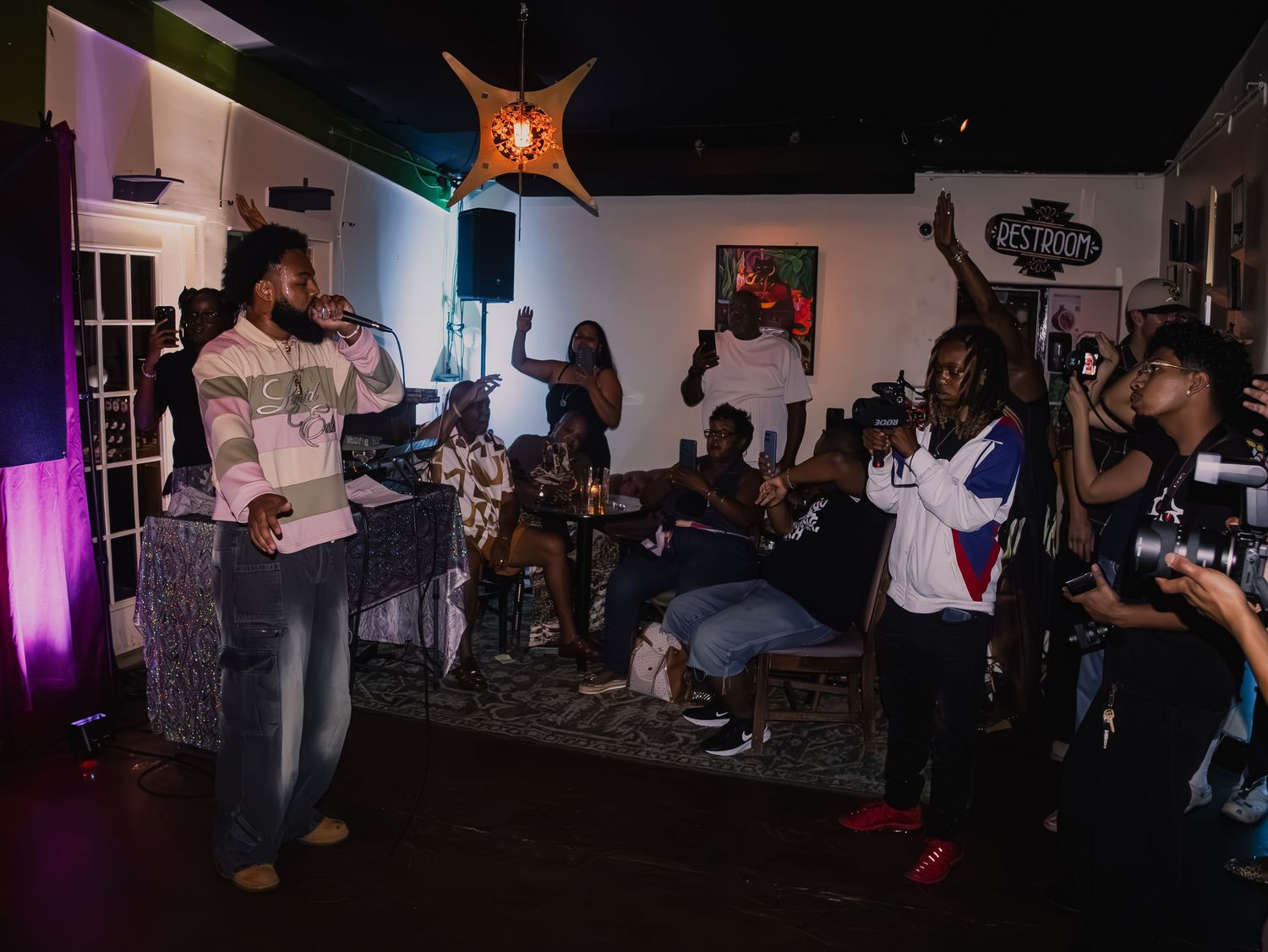 Live performance with crowd and musicians visible in intimate venue setting.