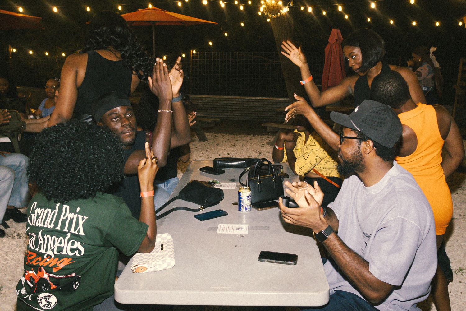 People sitting at tables during a nighttime gathering under string lights.