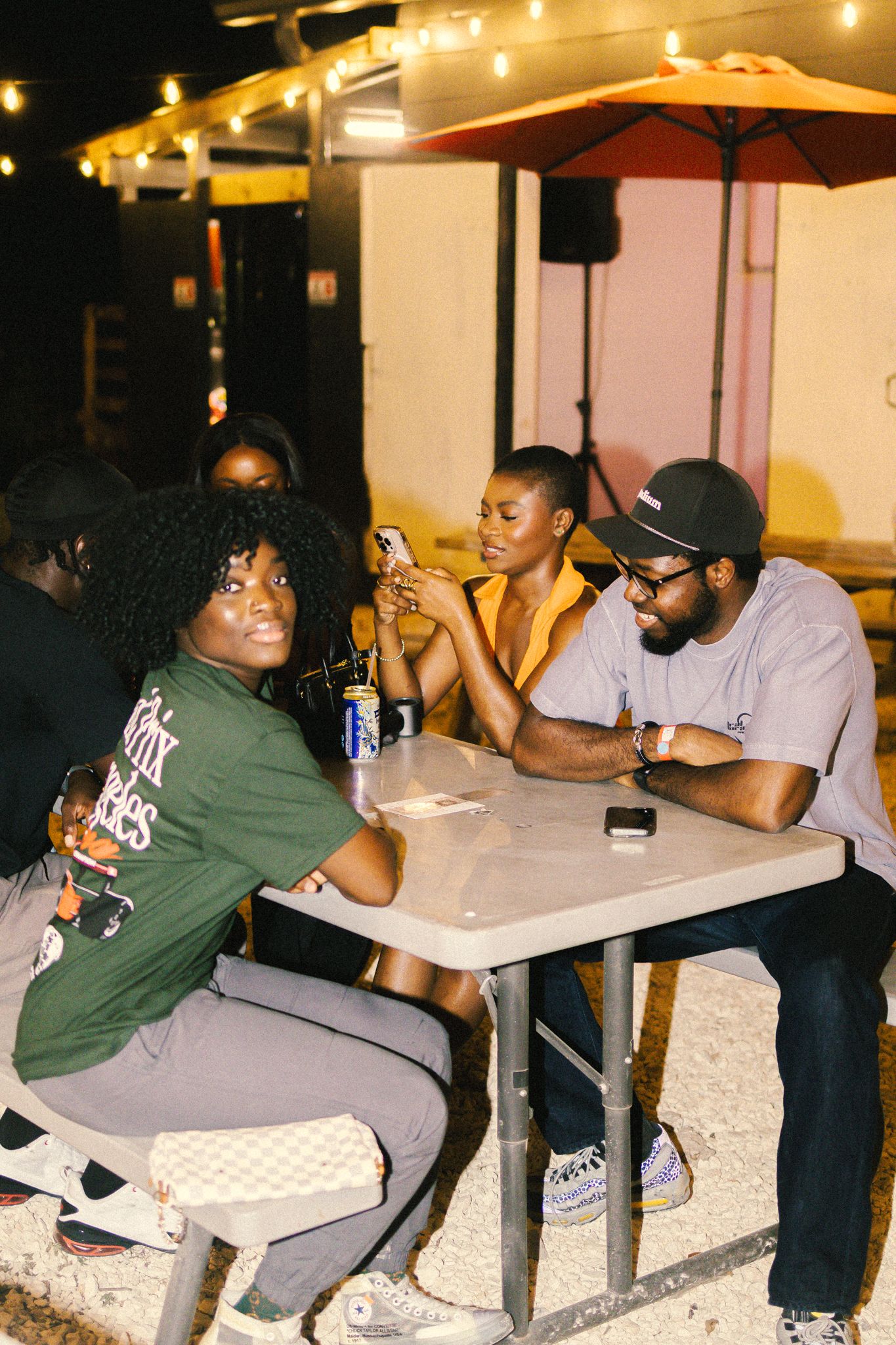 Group of people sitting at outdoor tables under string lights at night.