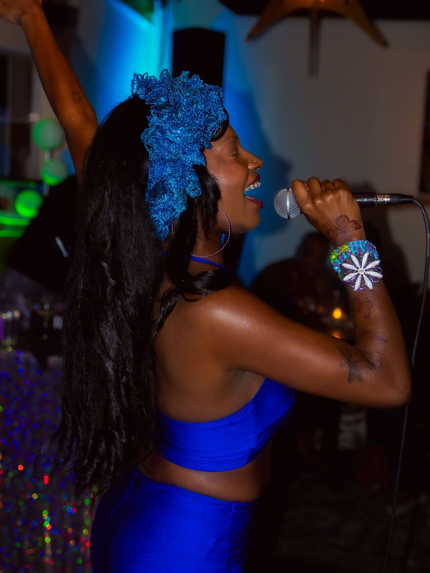 A singer in blue performs with dynamic energy under atmospheric lighting.