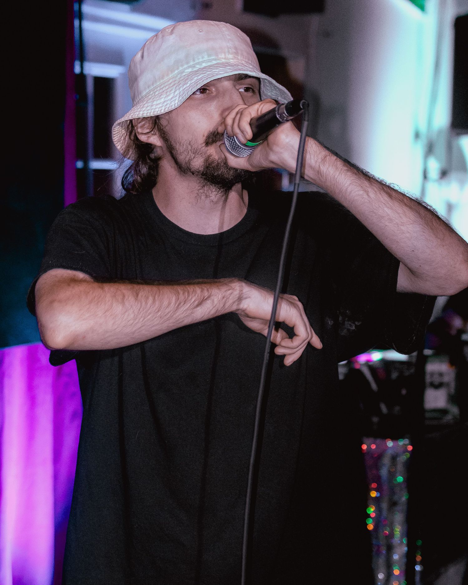 Performer in baseball cap delivering energetic rap performance with expressive hand movements.