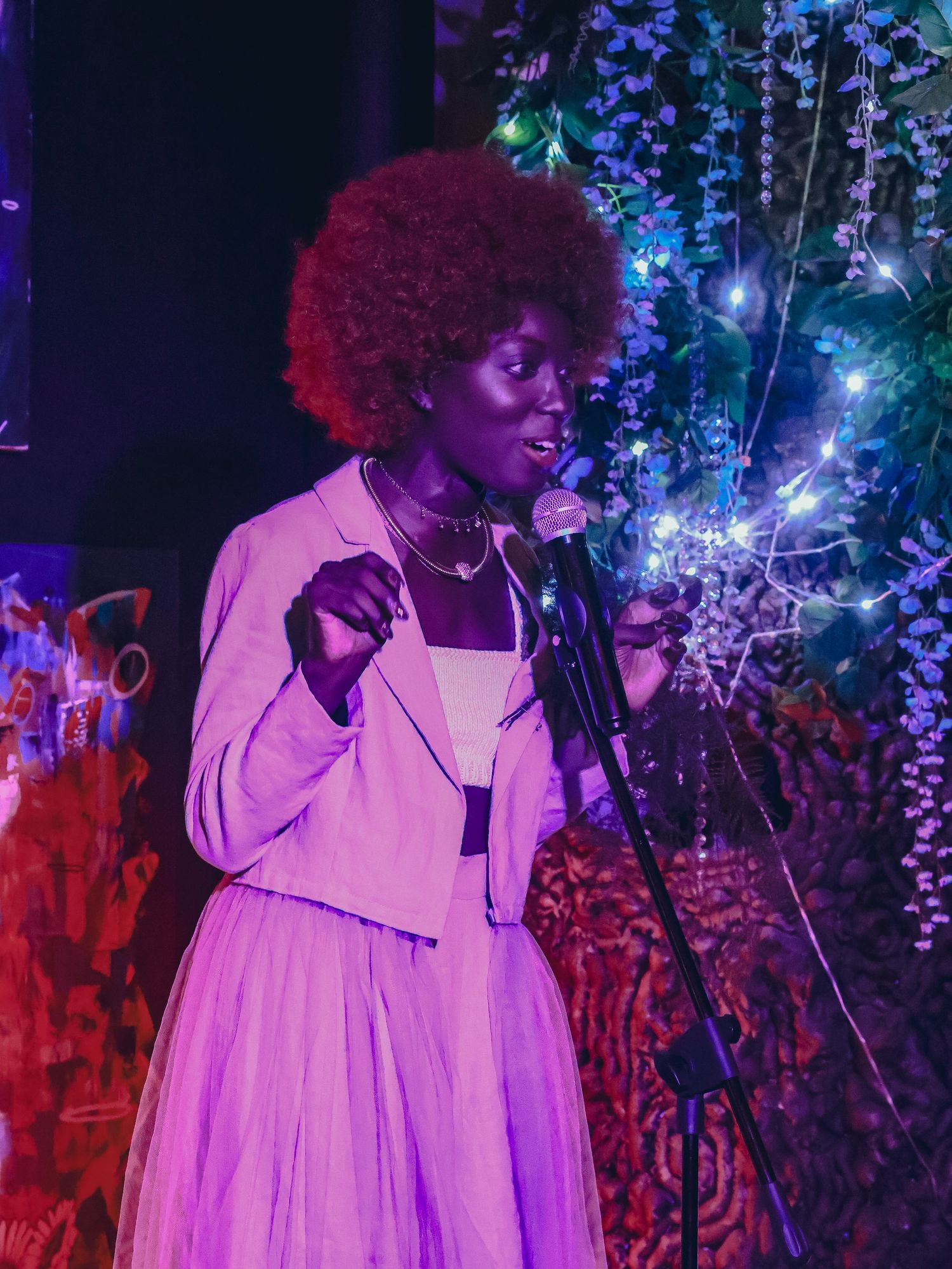 A singer performs on stage surrounded by decorative lights and purple ambiance.