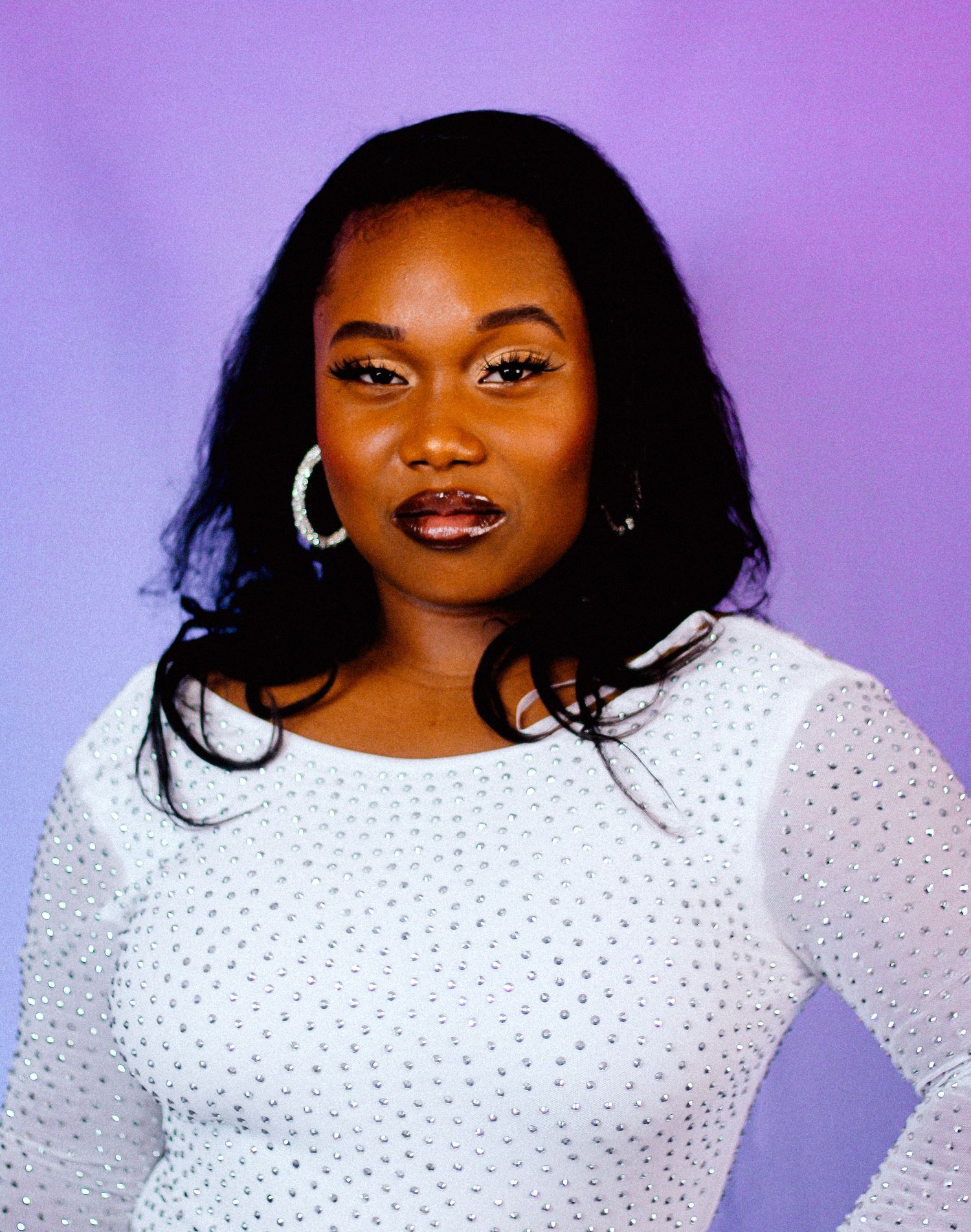 Fashion photo with white sequined top and dramatic makeup against purple backdrop.