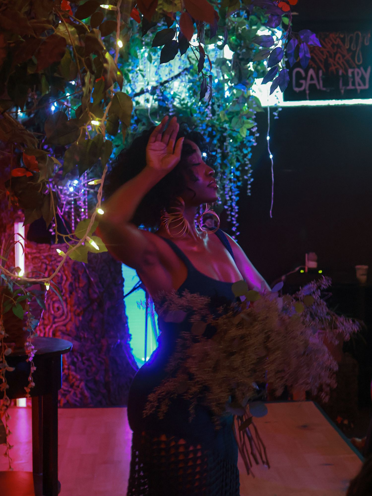Nightclub scene with colorful lights and hanging floral decorations.
