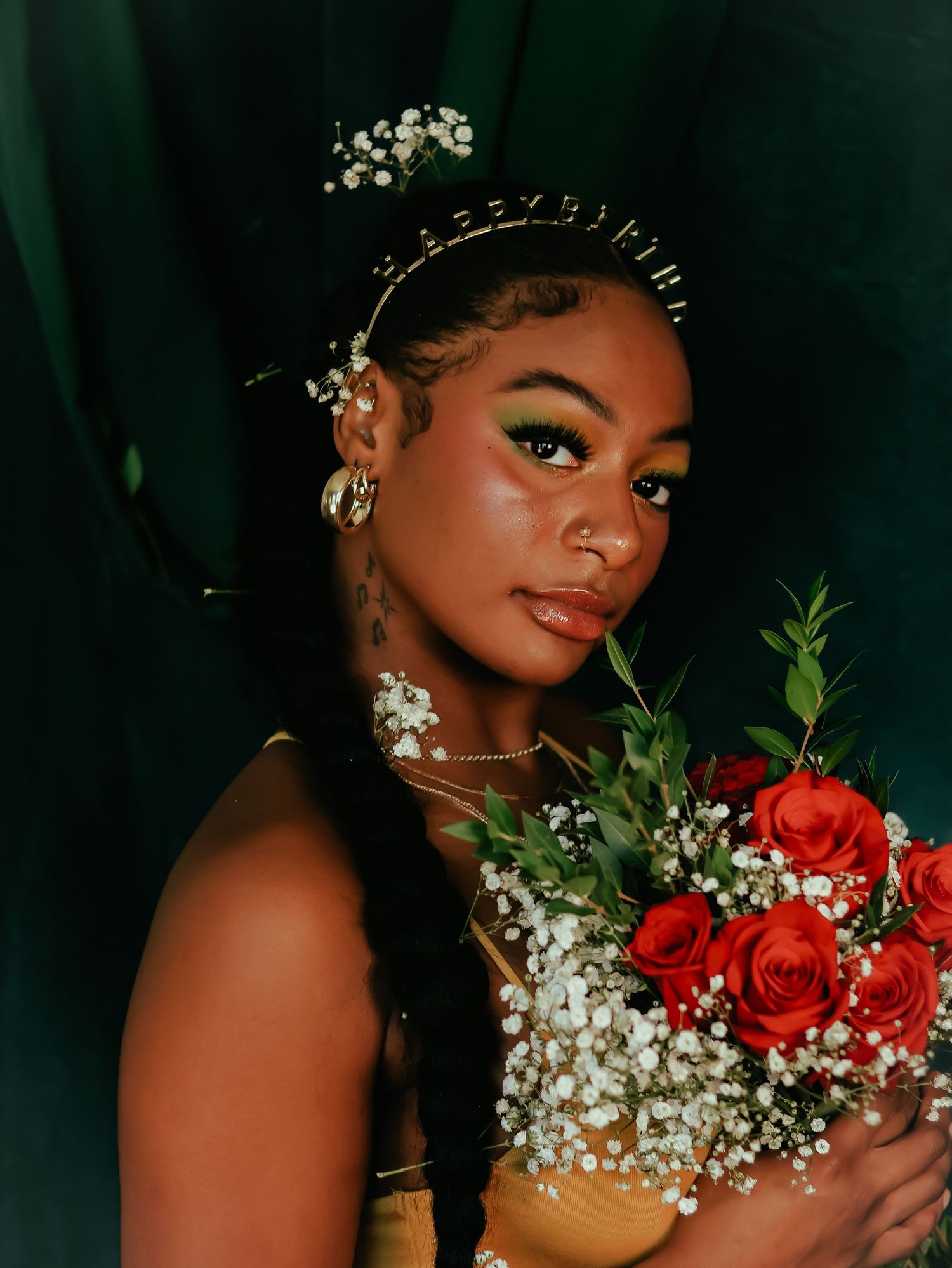 Glamorous portrait with red rose bouquet and floral crown against dark backdrop.