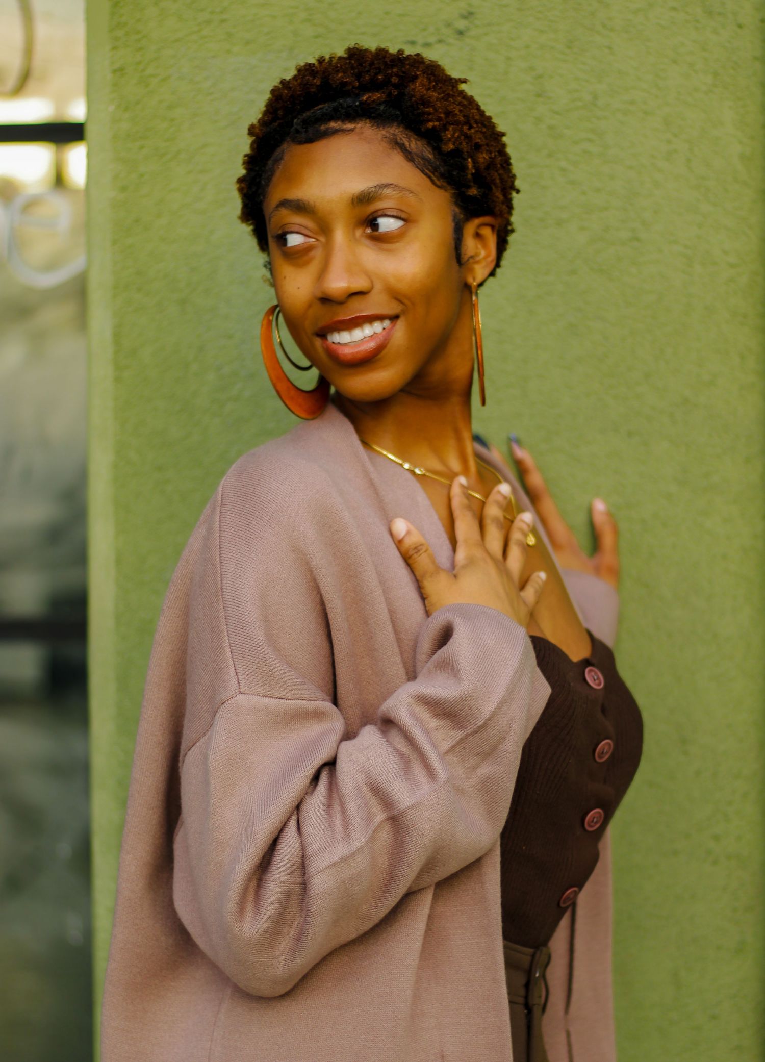 Candid poses against green wall showcasing natural expressions and casual style.