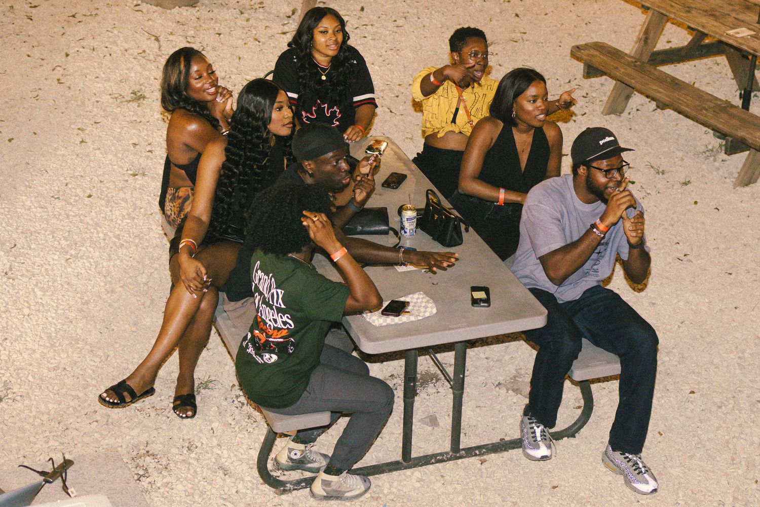 Friends socializing at picnic tables during a nighttime gathering.