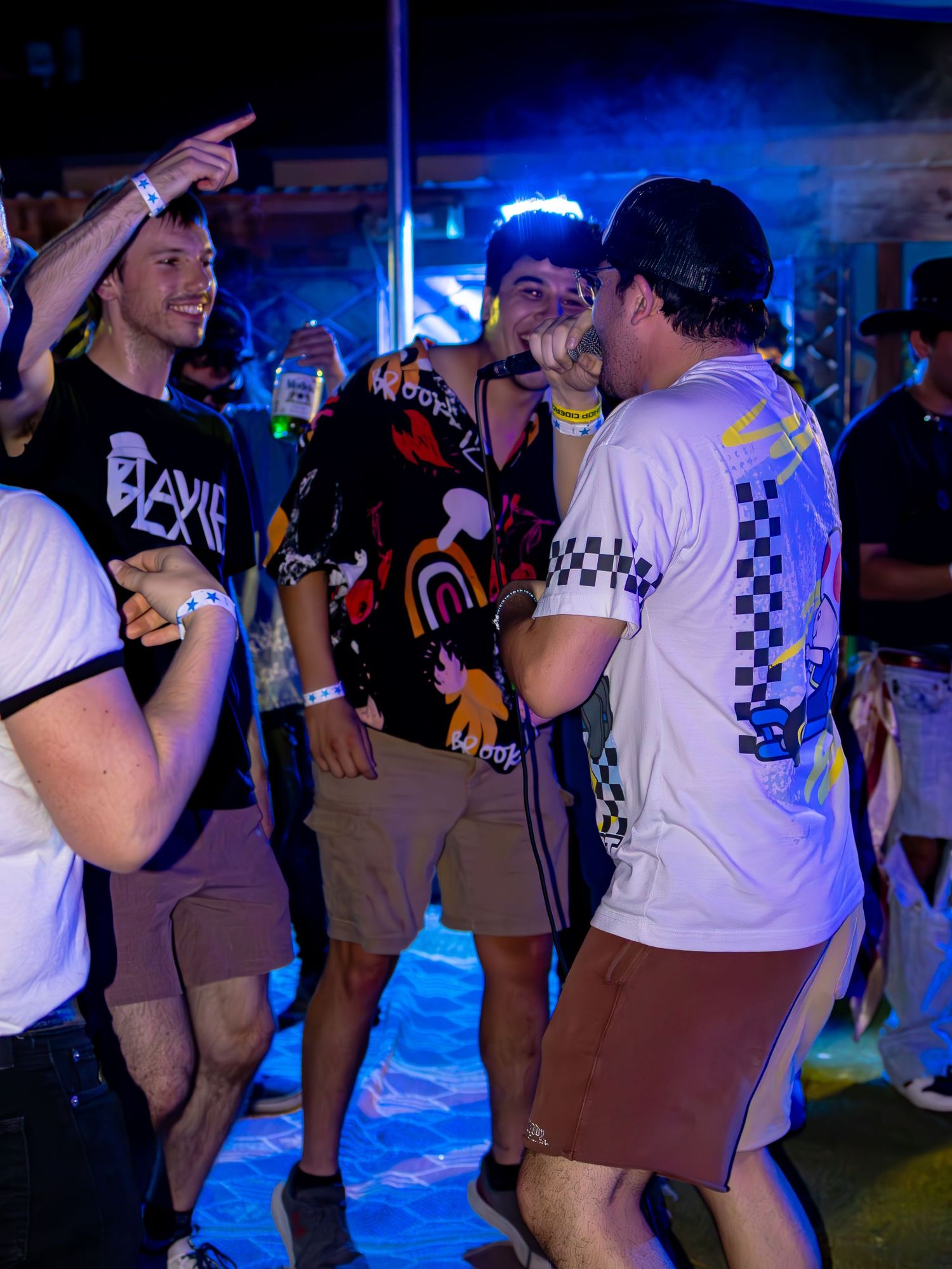 Group performing at night venue with blue lighting and checkered pattern shirts visible.