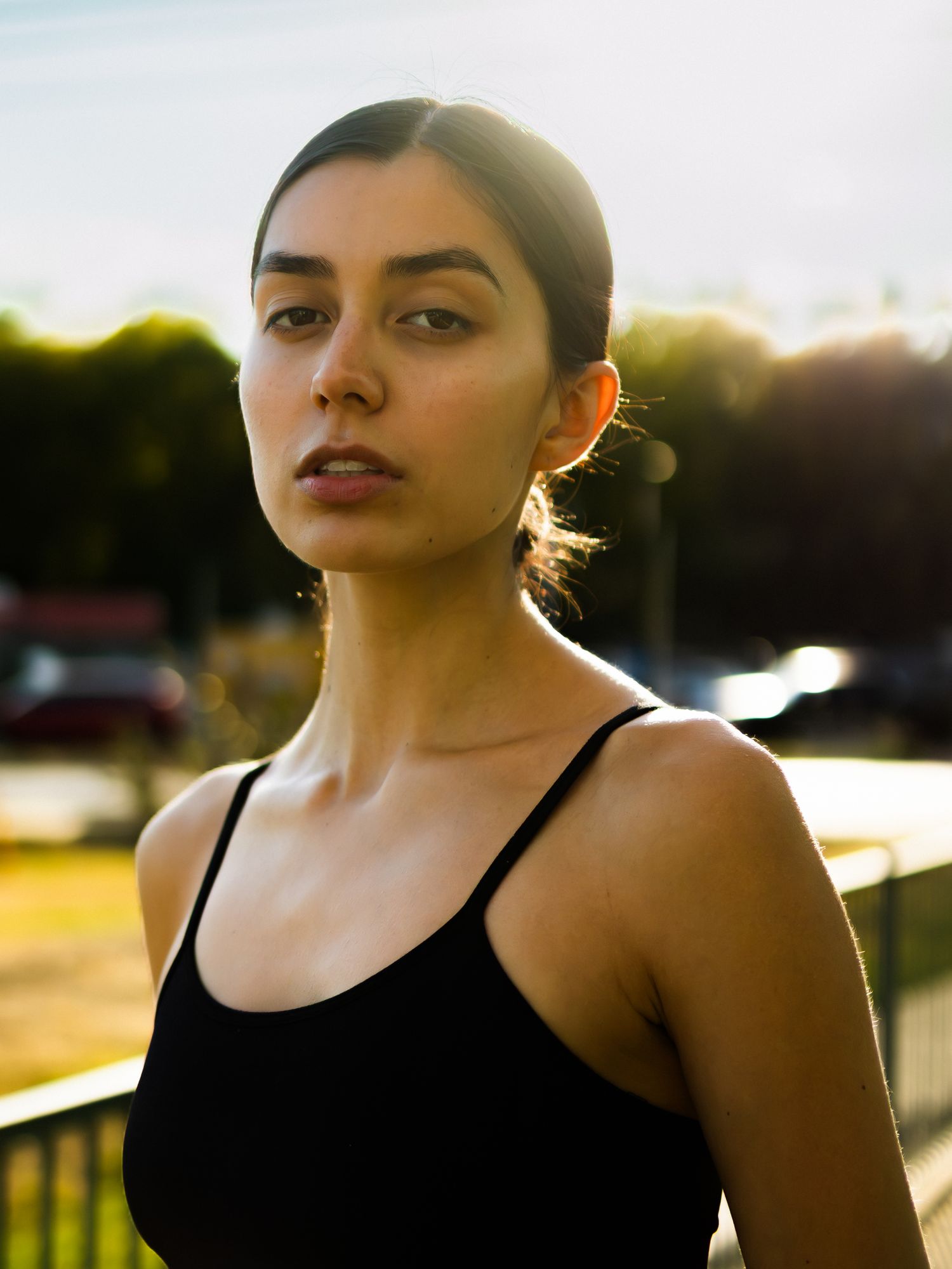 Dramatic sunset lighting illuminates figure in black athletic wear against urban setting.