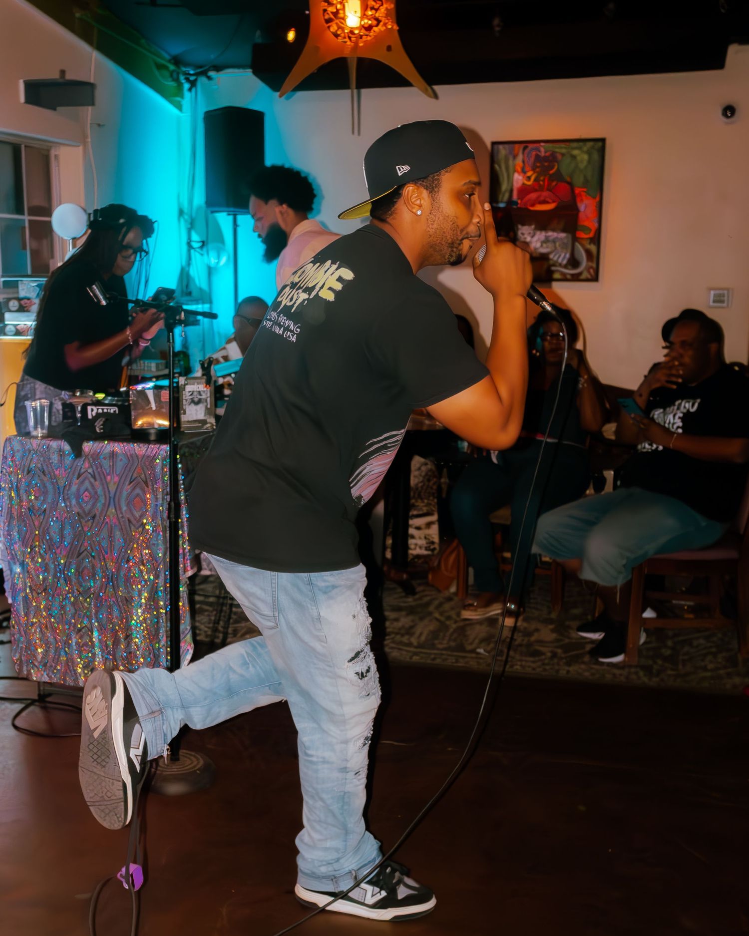 Performer in casual attire strikes dynamic pose during hip hop performance on stage.