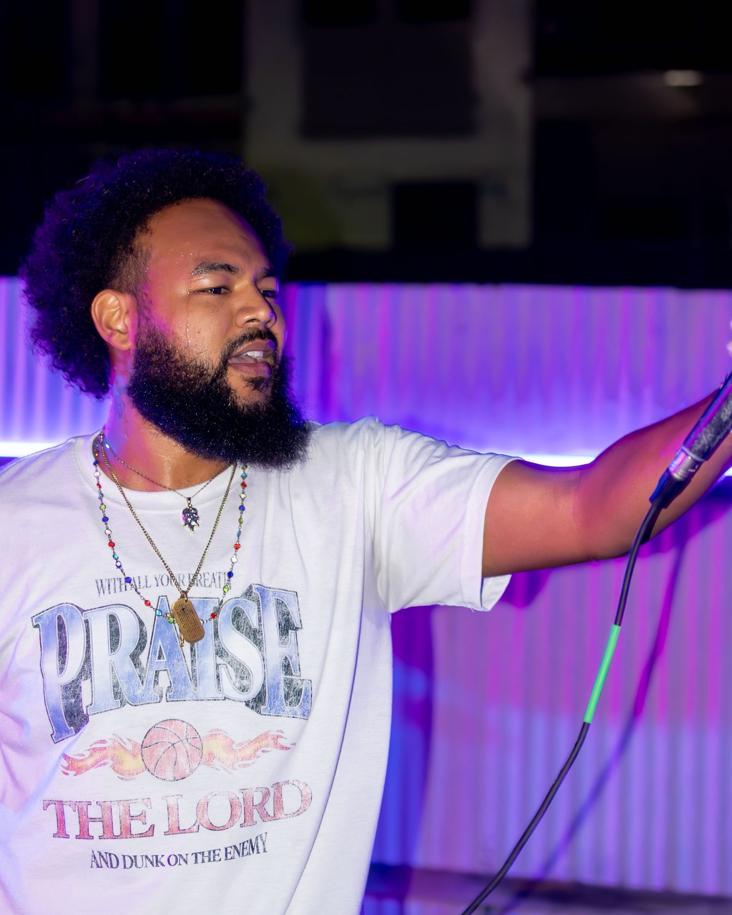 Musician in casual attire delivering passionate performance with illuminated backdrop.