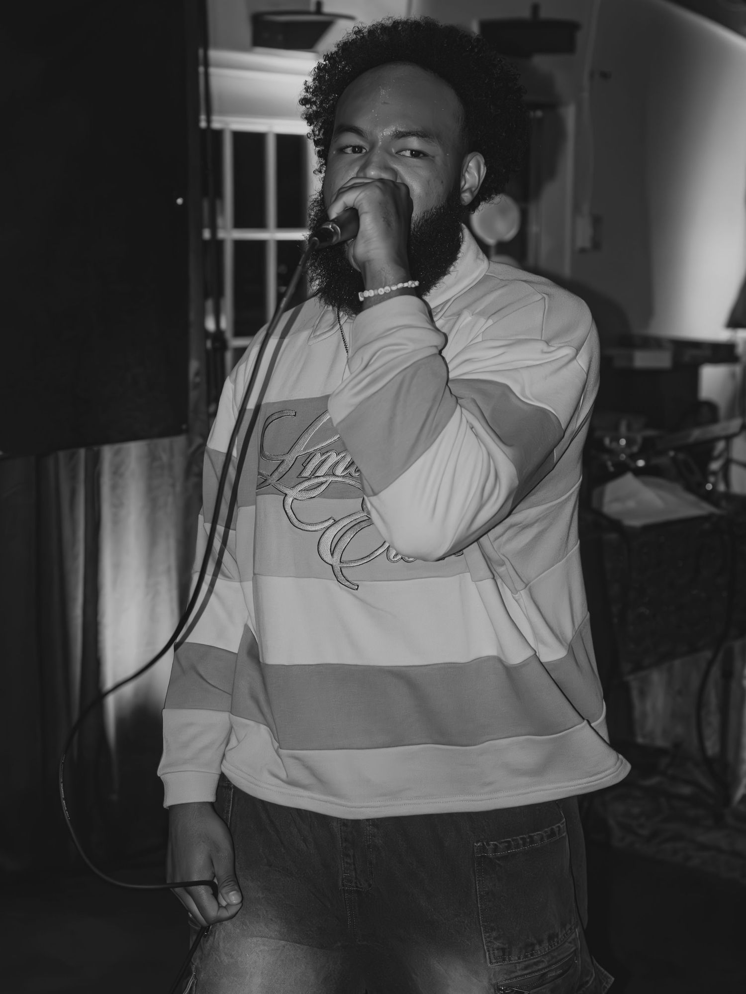 A black and white photo of a performer singing emotionally into a microphone.