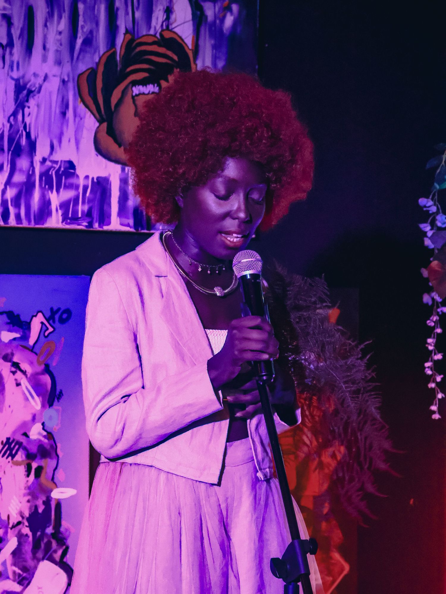 A musical performance captured under vibrant purple stage lights with dramatic shadows.