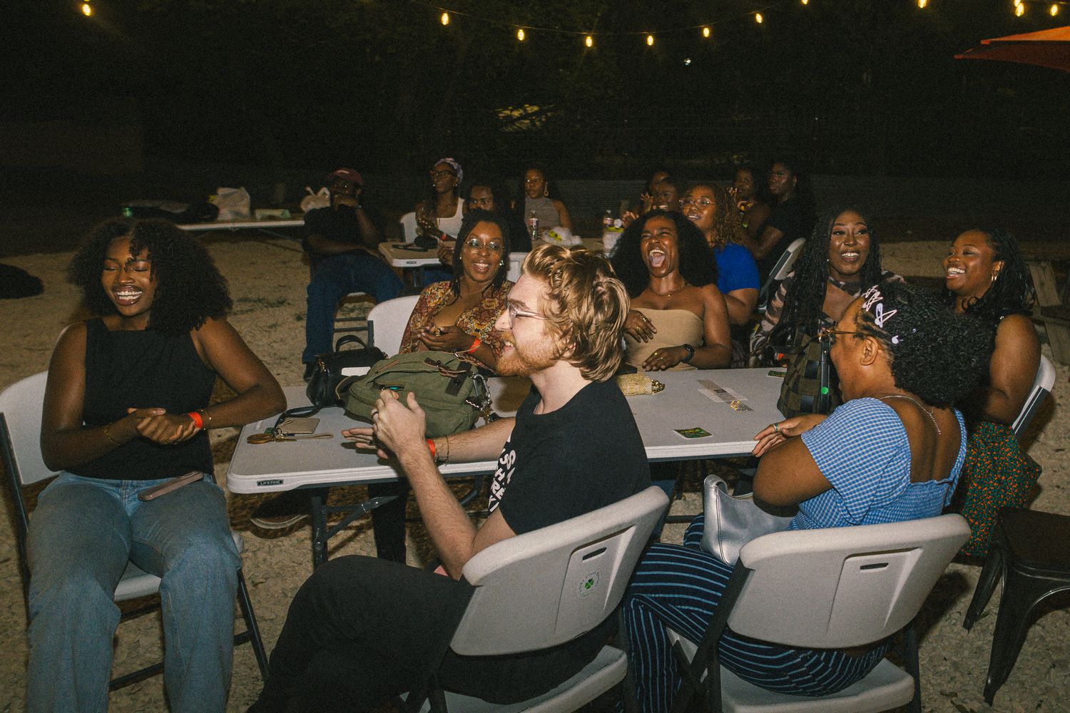 Guests seated at white tables during a nighttime outdoor social event.