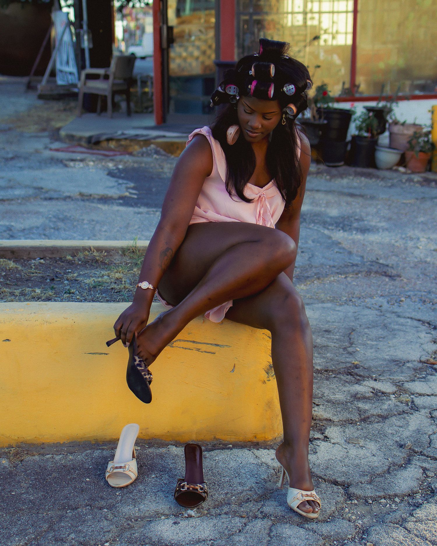 A person in casual attire sits on a yellow painted curb.