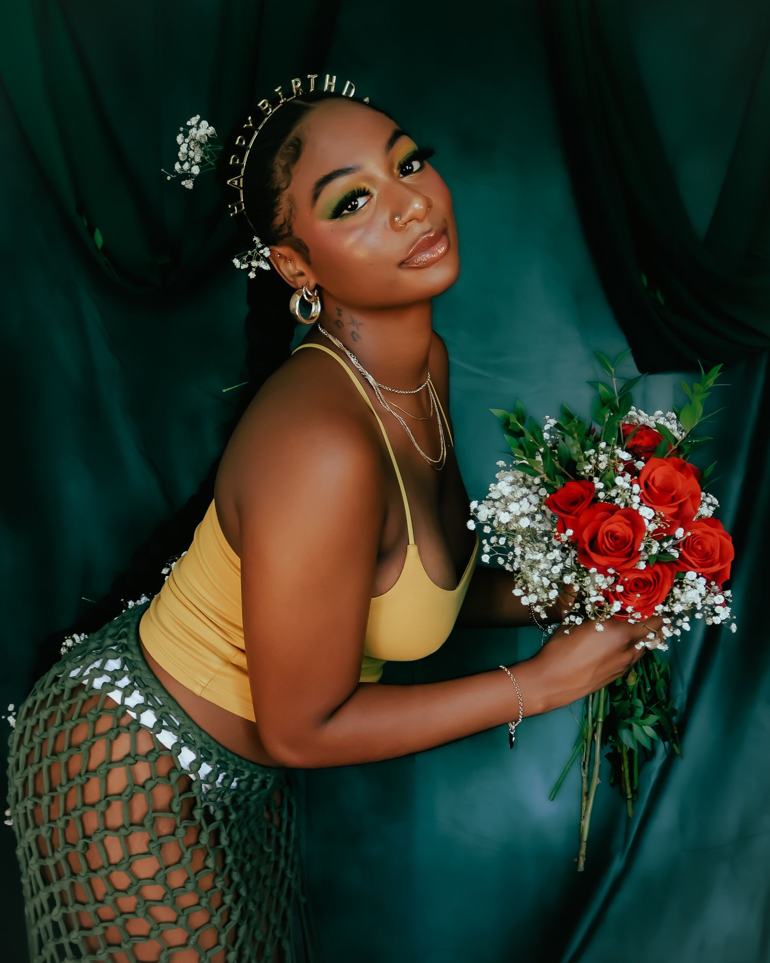 Dramatic portrait with red roses and baby's breath flowers against emerald background.