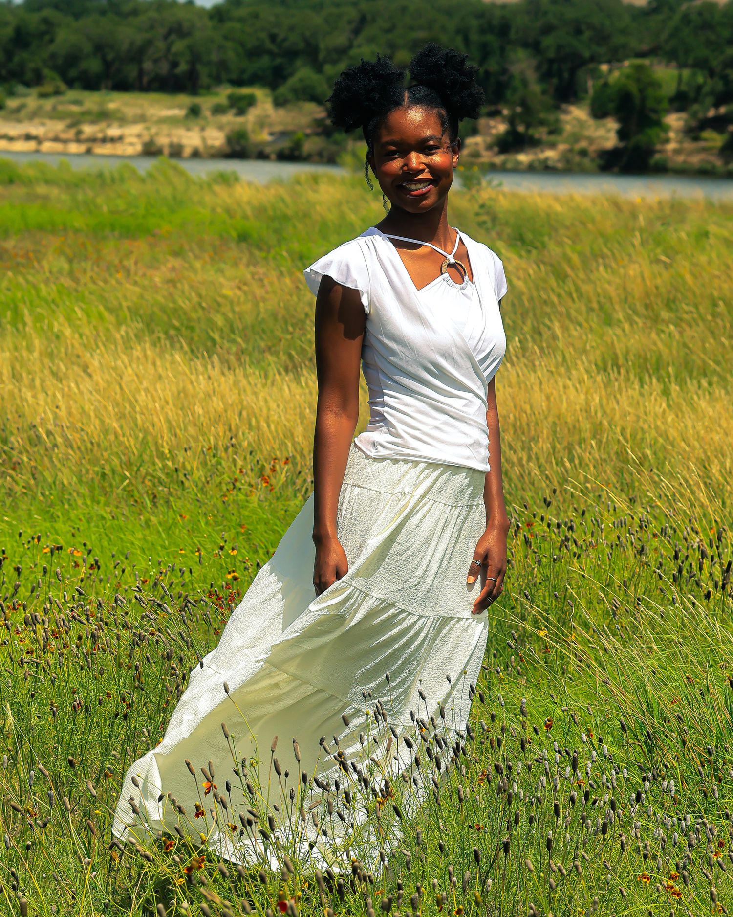 A flowing white dress catches sunlight in a natural meadow setting.