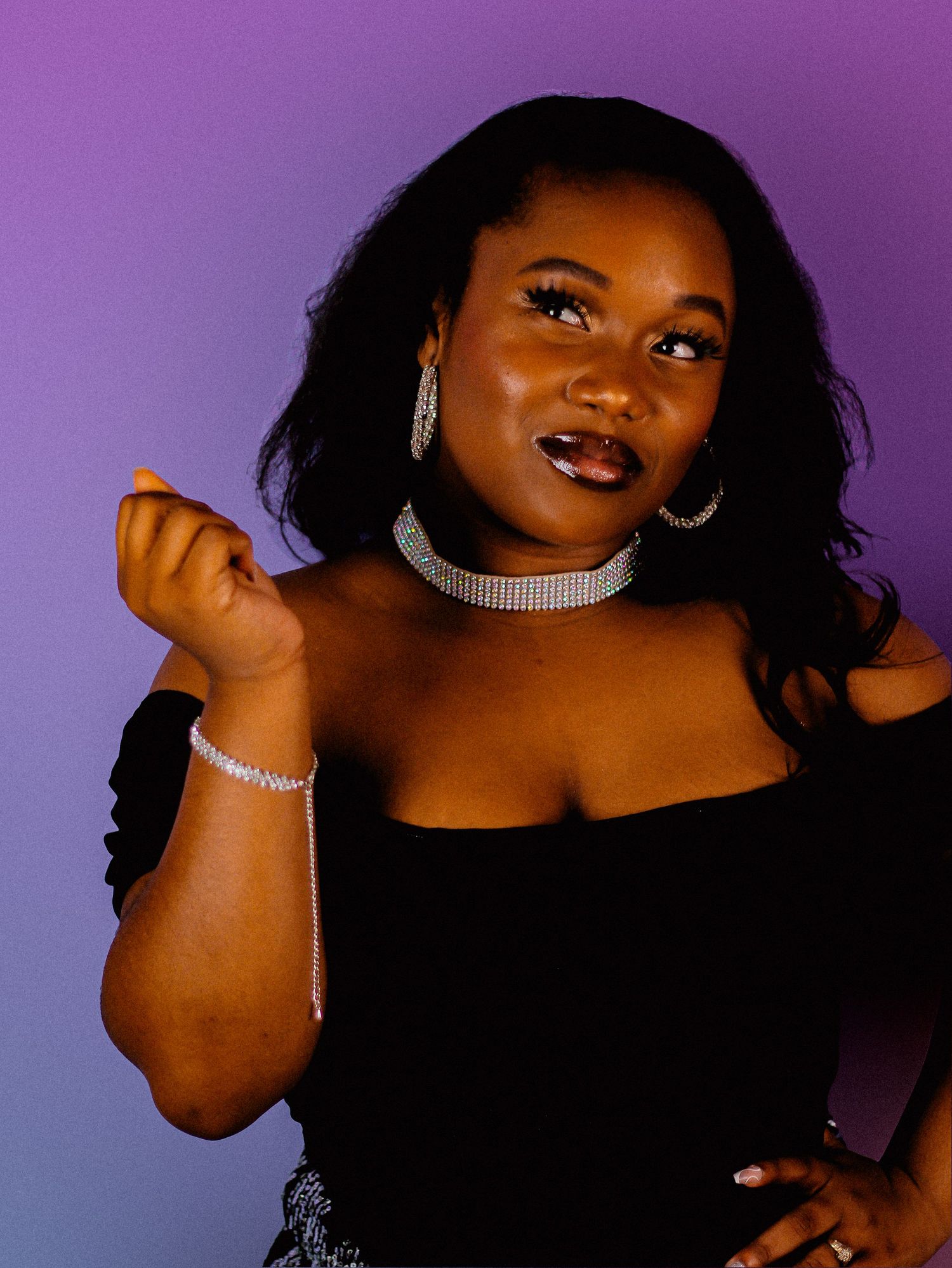 Glamour portrait in black outfit with rhinestone accessories against purple background.