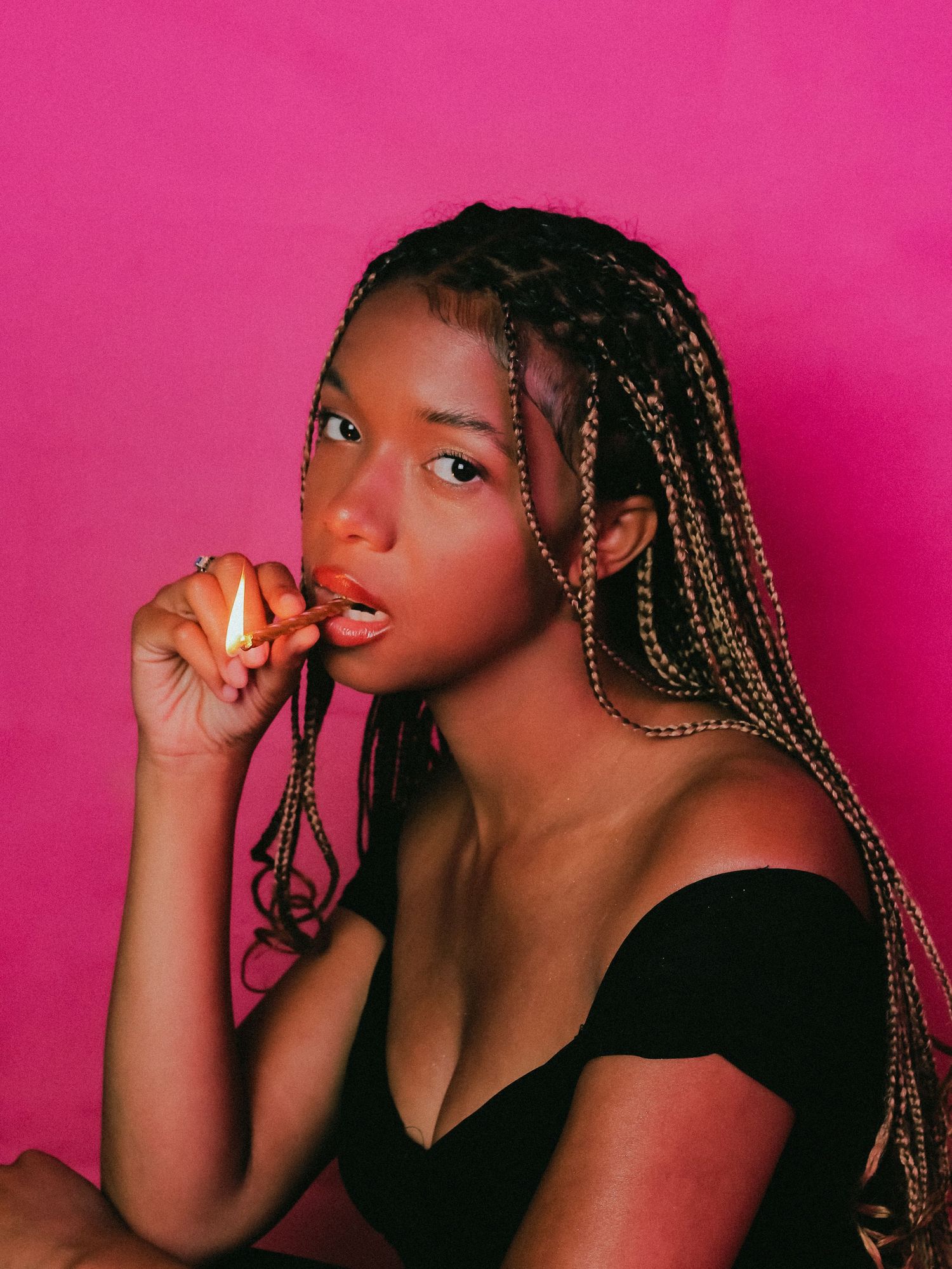 Portrait against pink background with braided hair and black top creating a dramatic artistic mood.