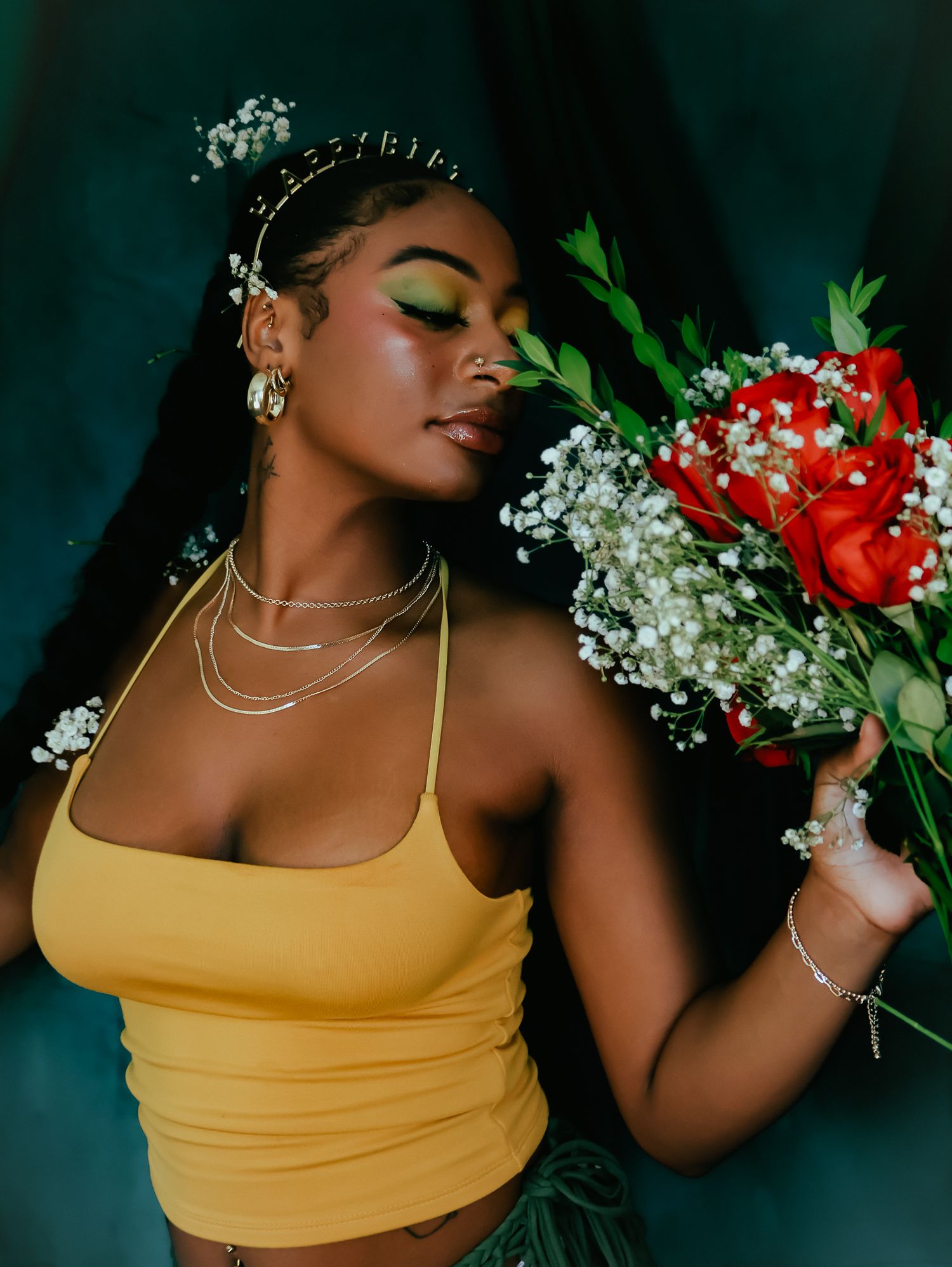 Ethereal photoshoot with yellow top and delicate white flowers in dark setting.