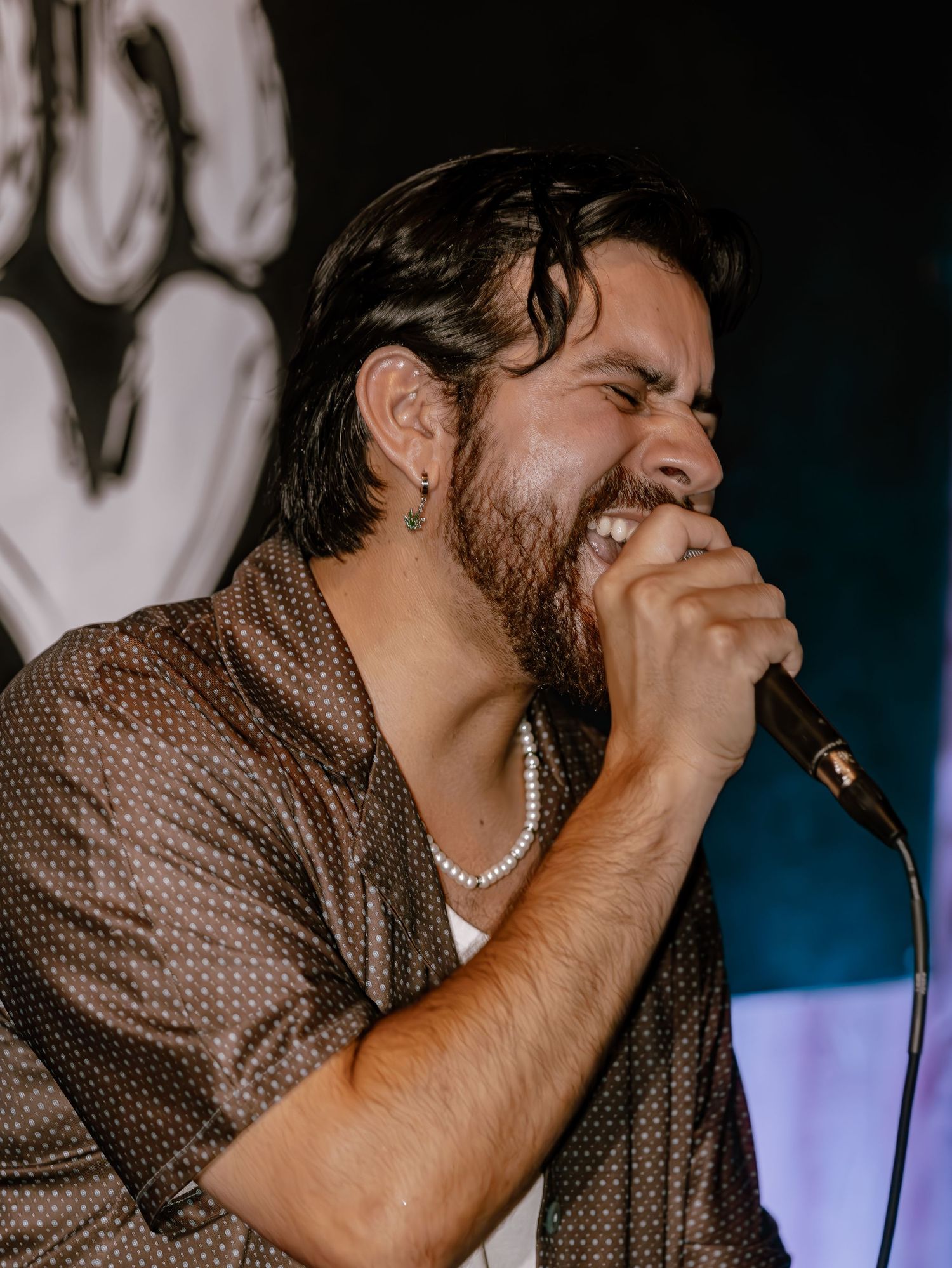 Energetic singer performs with intensity while holding microphone against dark background.