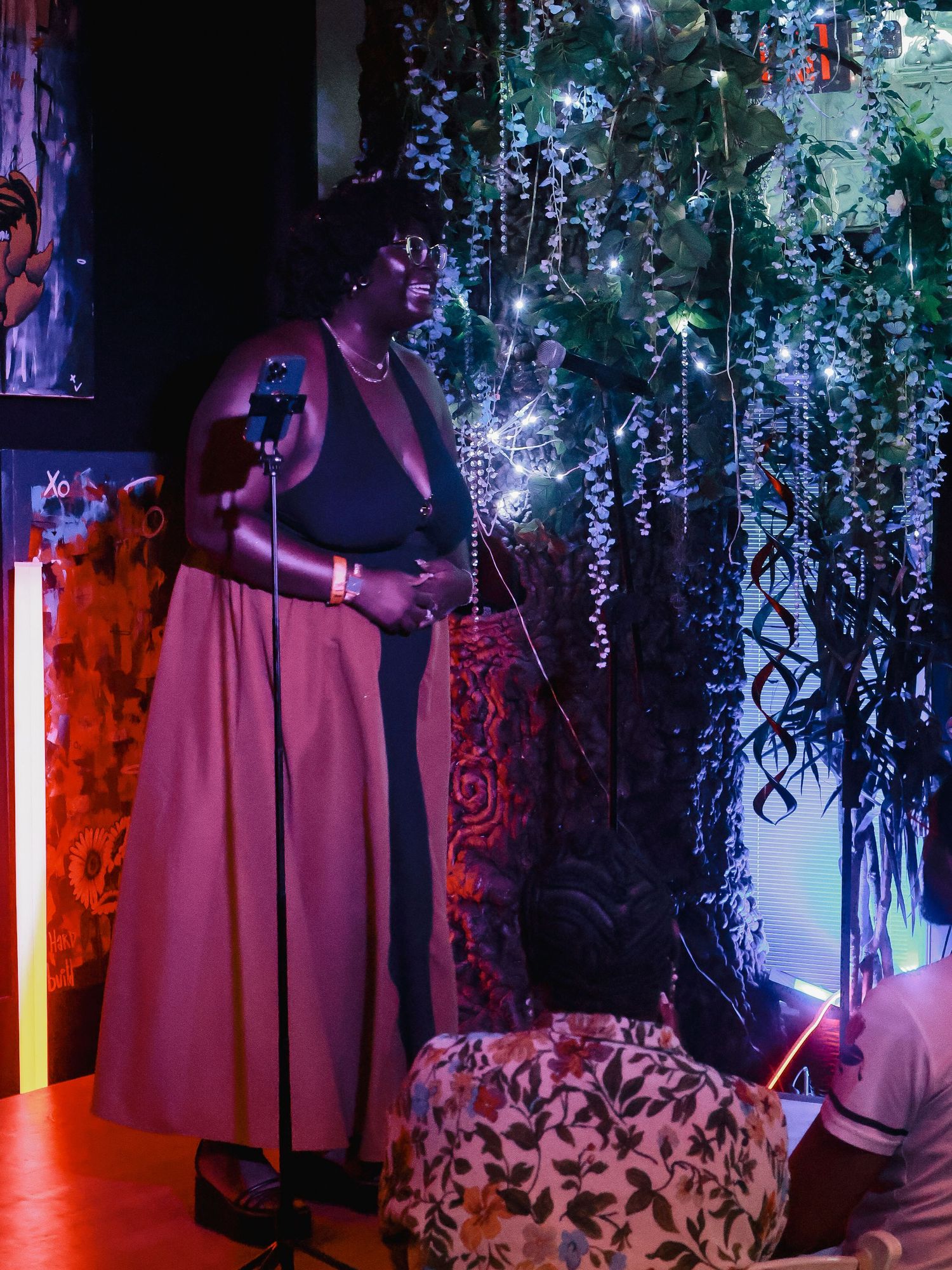 Artistic stage design combining purple lighting, hanging vines, and elegant fabric draping.