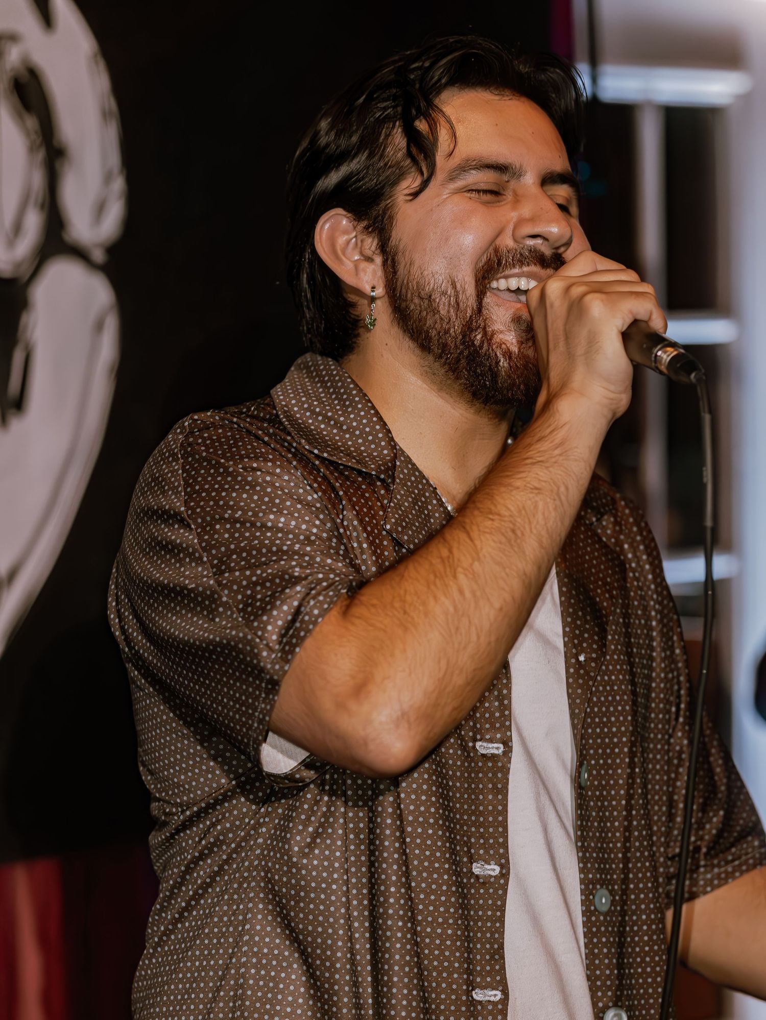 Close-up of performer in brown patterned shirt singing with emotion.